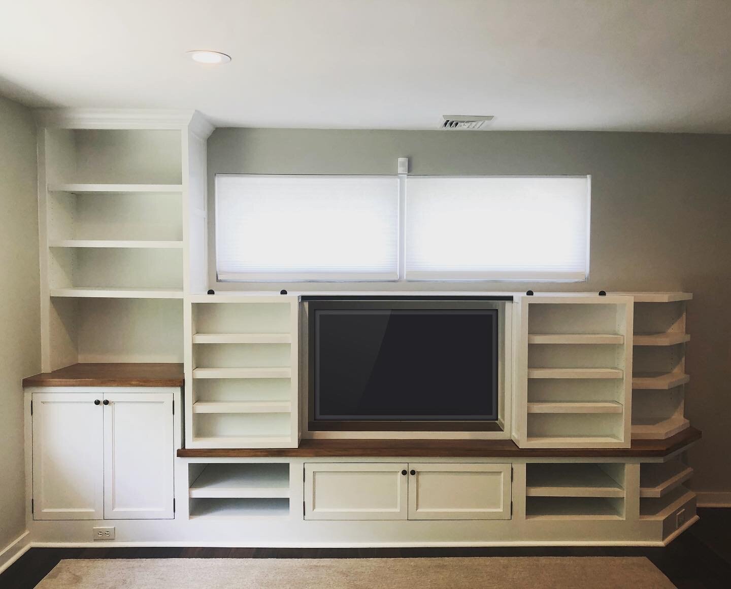  In lieu of standard barn doors I came up with an idea for shallow sliding shelf cases as you can see in the picture above. Mounted on mini-barn door tracks, the cabinets glide open to reveal the TV within. They sit just above the countertop and have
