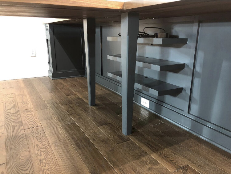  Underneath the desk are two tapered legs made from solid maple. These support the desktop above as well as the embedded steel reinforcements that are used to strengthen the desktop. The floating shelves along the rear wall provide a place for compon