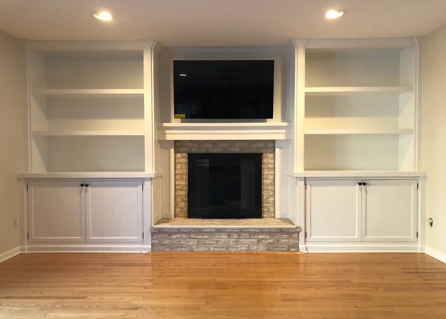  The finished product has lower cabinets for storage, upper bookshelves, TV mounted over the fireplace and a new mantle.  