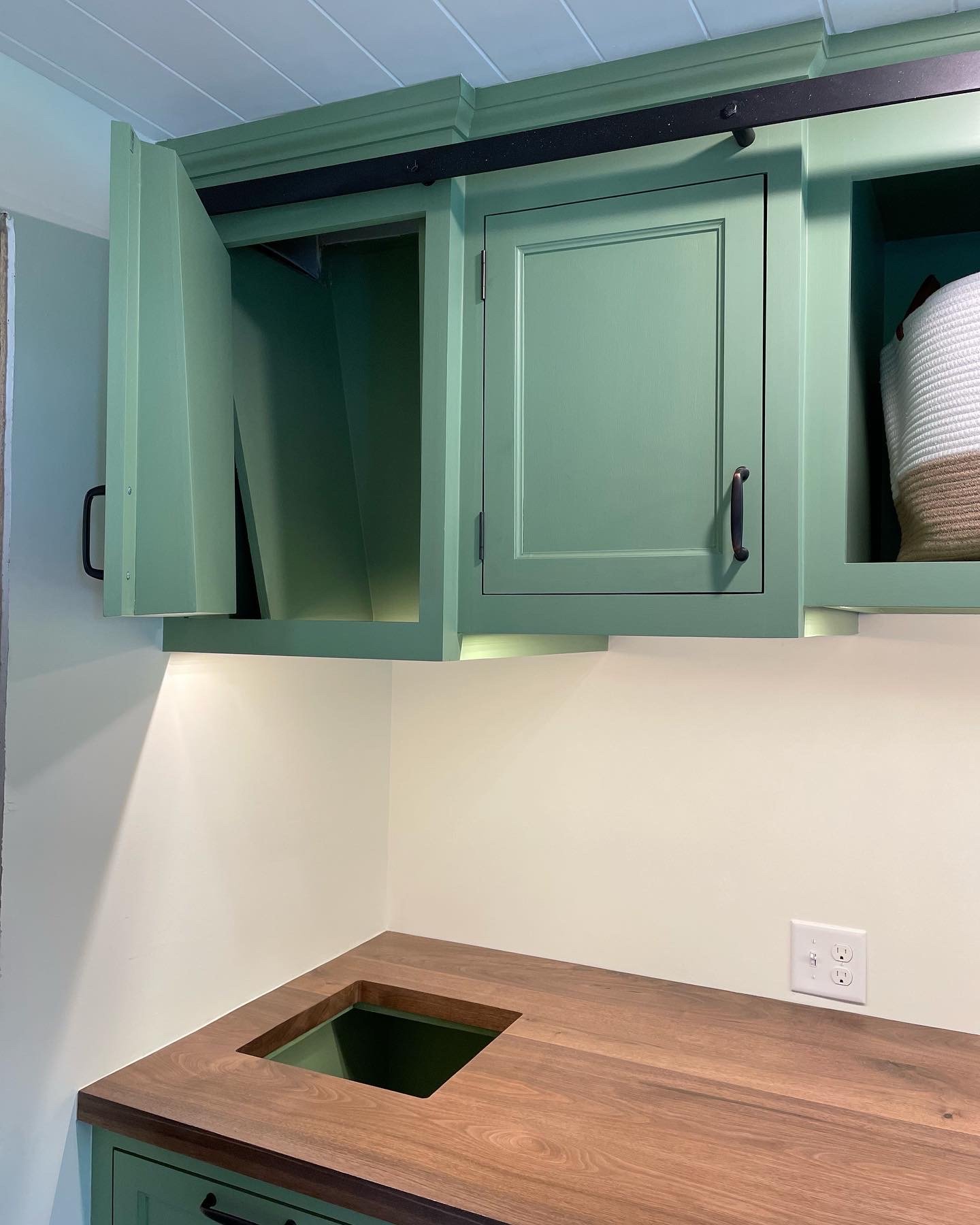  On the left side of the room is a false cabinet that conceals a laundry chute which originates upstairs in our master bathroom.  Clothes pass through this false cabinet, down through the opening in the countertop, and then collect in a large pull-ou