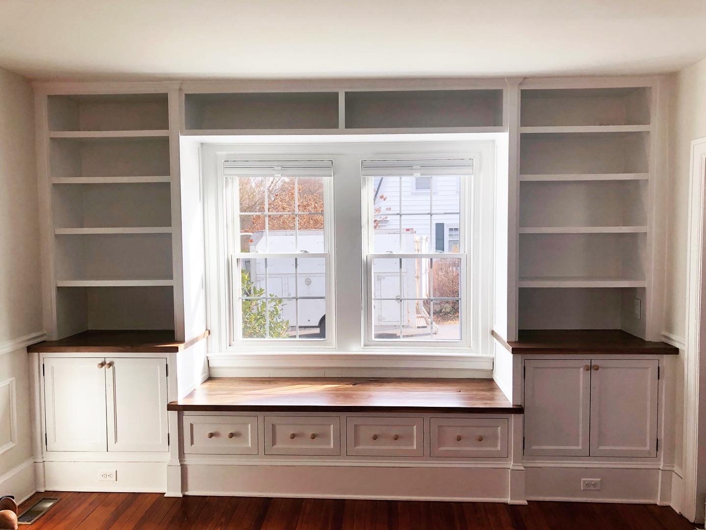  These built-ins are the larger of the pair and features flat panel doors and drawers, and black walnut countertops. The kids of the house were staking claims to the window seat even before it was finished.  