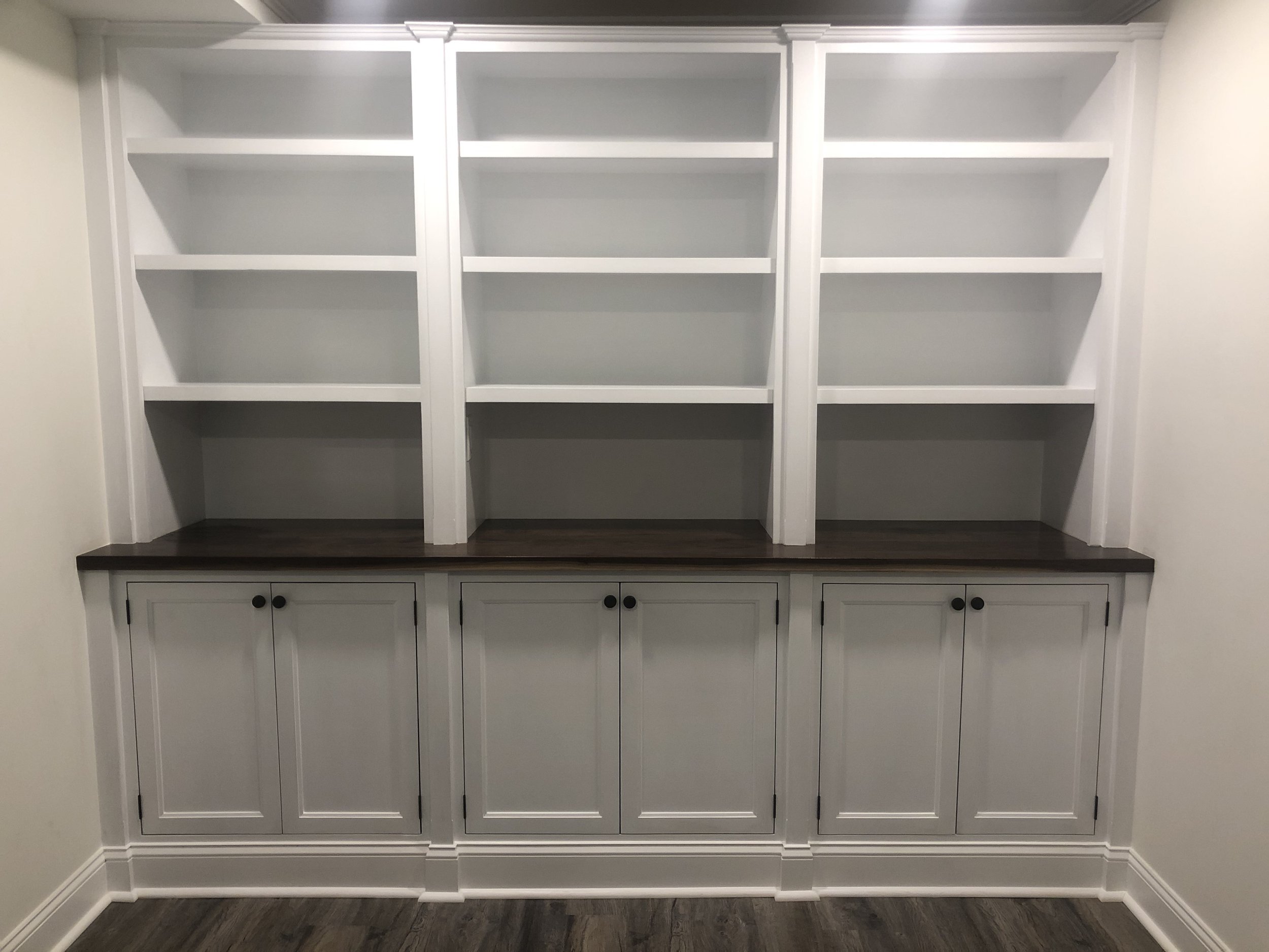  The finished product features inset flat-panel doors, a black walnut countertop, and a pull-out shelf inside the lower center cabinet. 