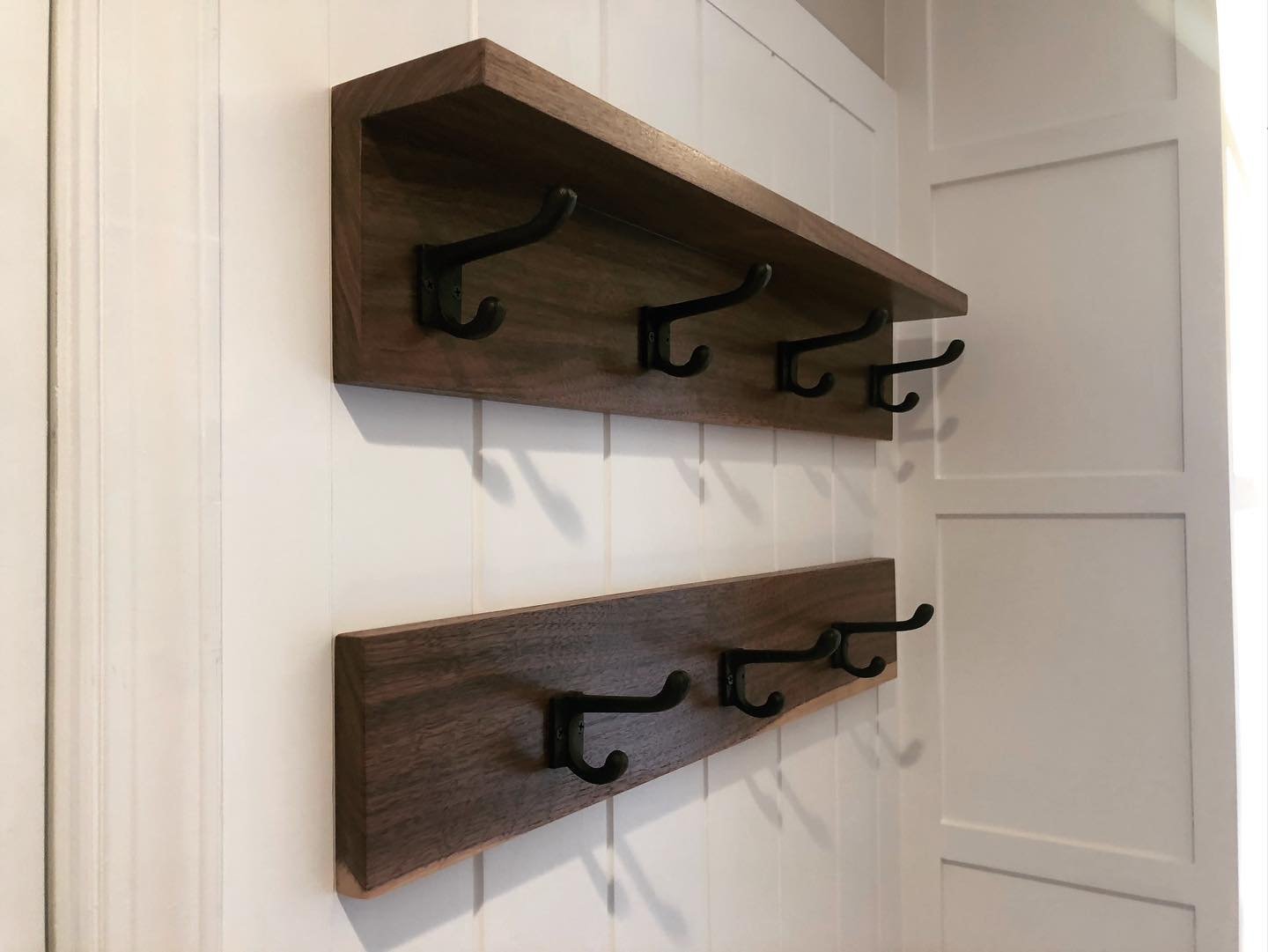  A close up of the hanging area. A double row of hooks is mounted on black walnut boards to match the benchtops, the shelf above provide additional storage for smaller items, and it’s all mounted on custom wide wainscot paneling.  