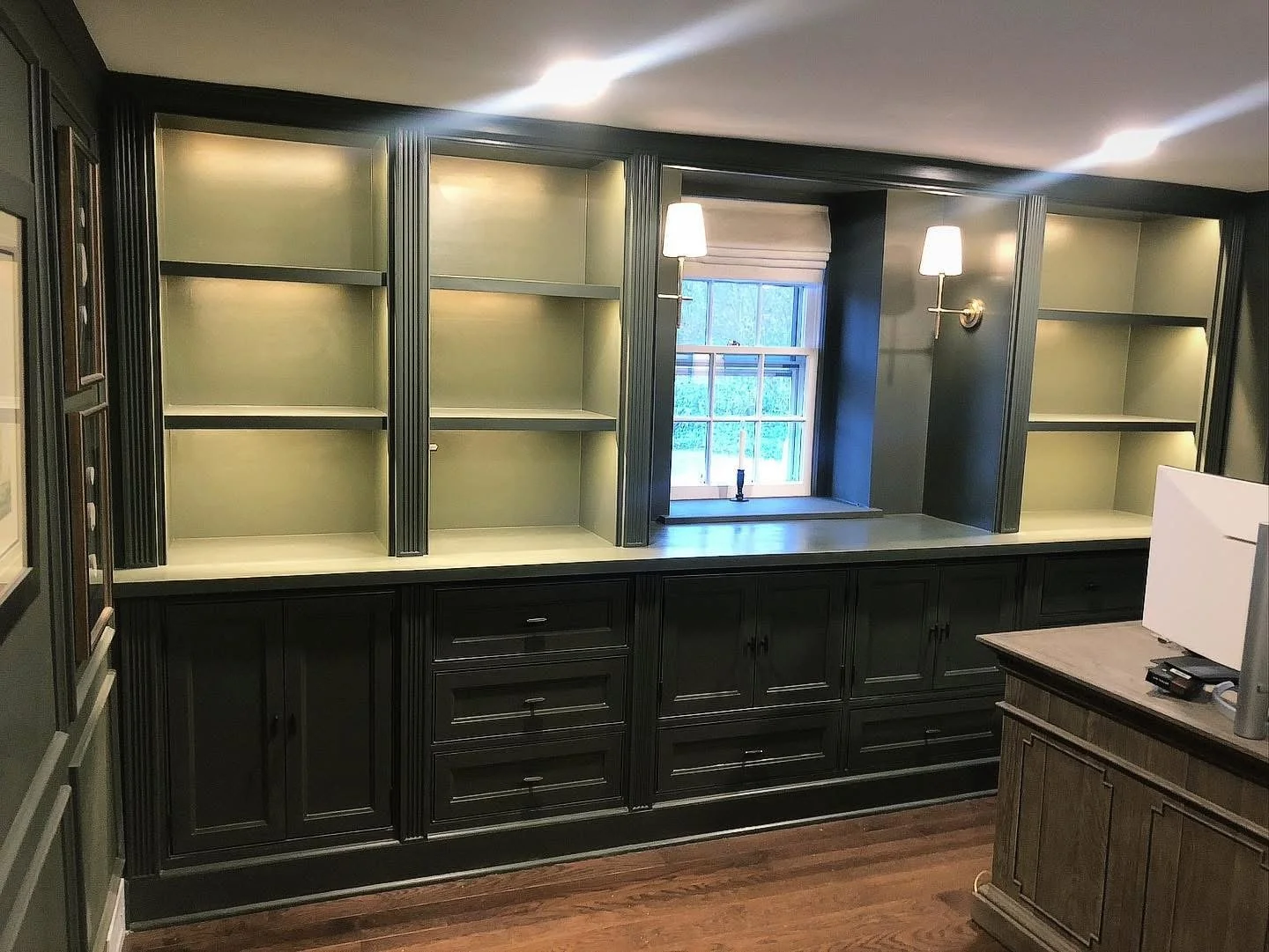  Matching the original wall color, Sherwin Williams “Shade Grown” (SW6188), the built-ins feature beaded face frames, inset flat-panel doors and drawers, and the under-shelf lighting and wall sconces add to the cozy feel of the room. Pull-out shelves