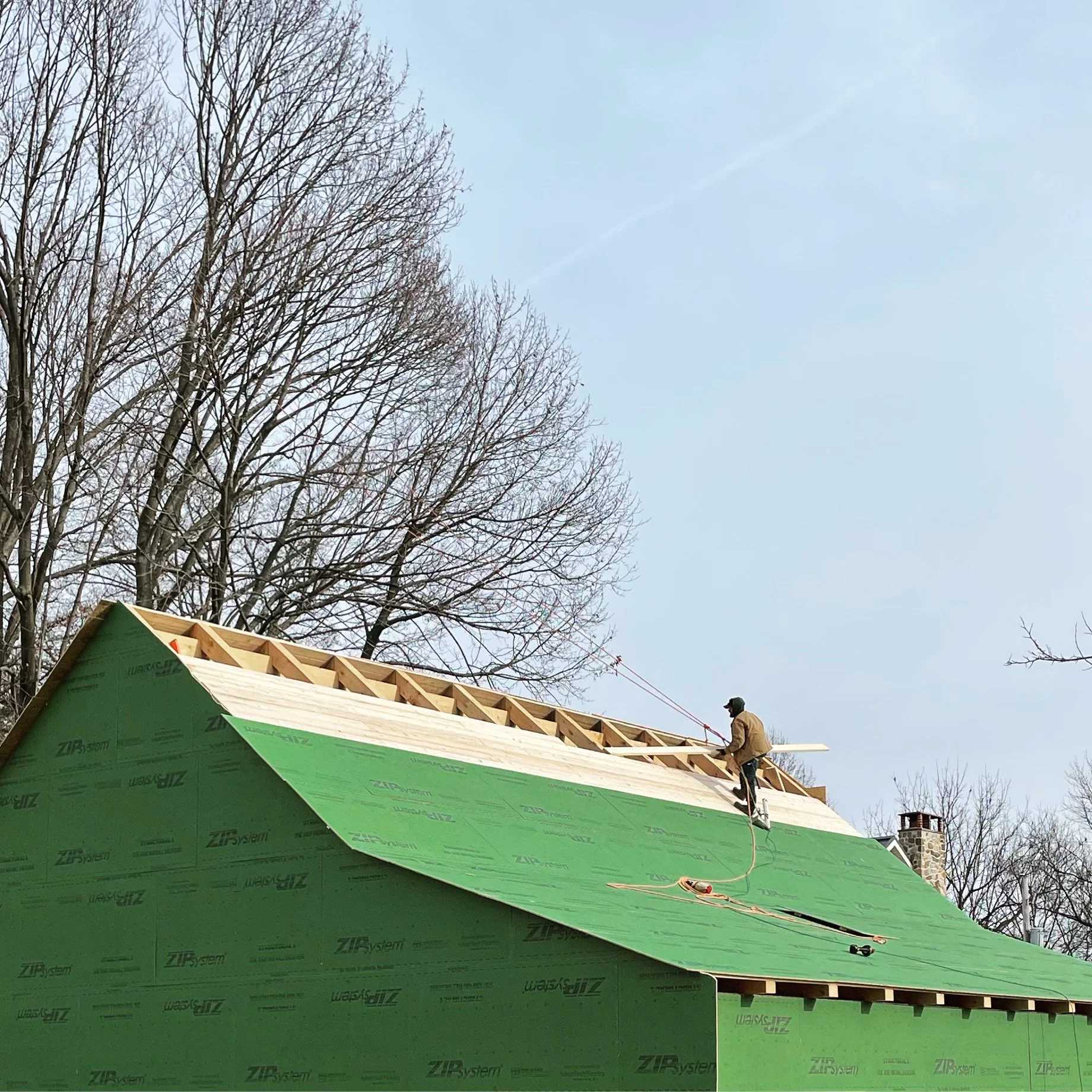  The roof consists of a layer of 2×6 framing covered in Zip Wall sheathing. In this picture I’m racing to get everything closed in before a snow storm was supposed to hit, and to keep myself secure I broke out my old tree climbing gear and tied mysel