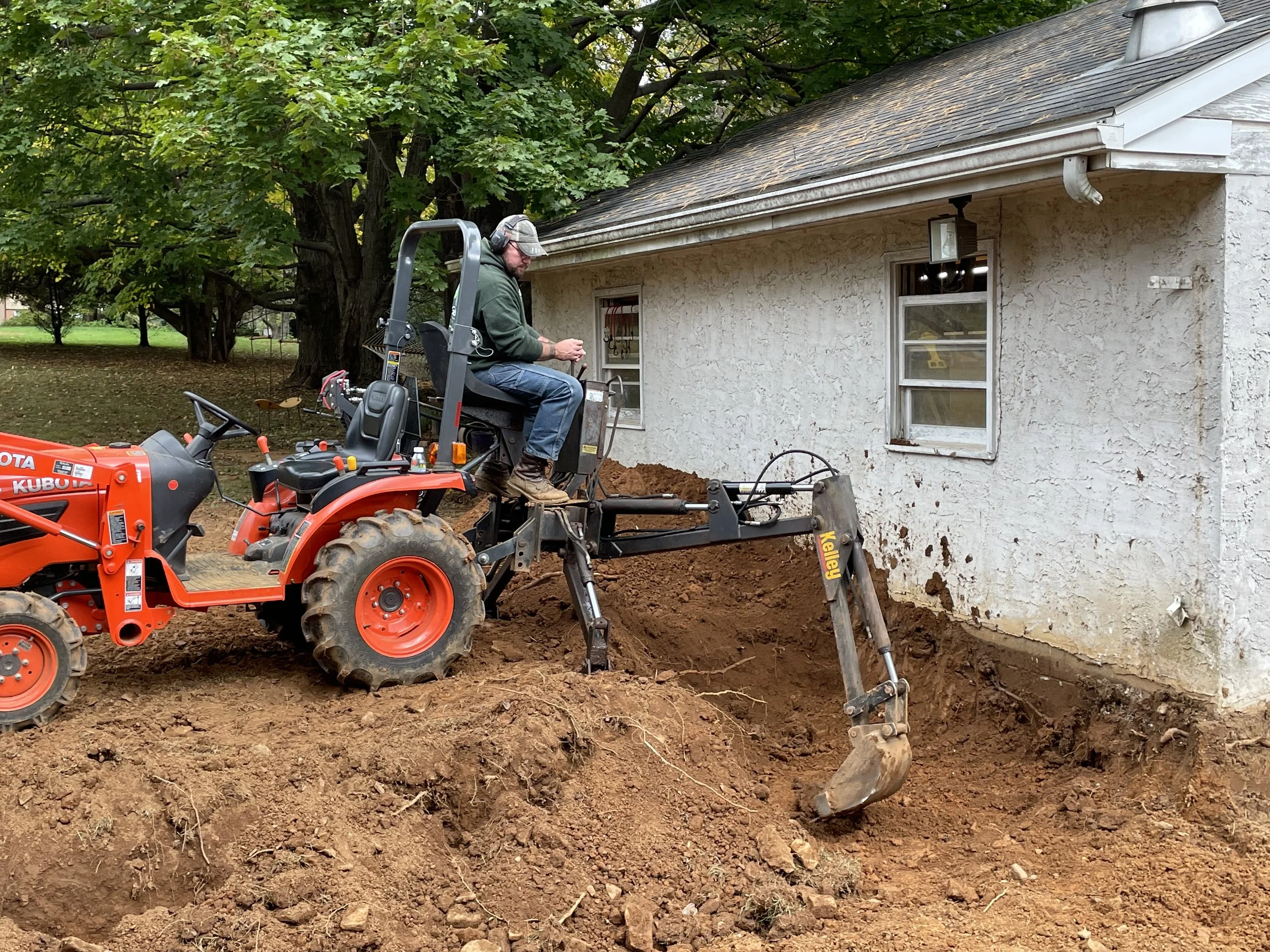  I did the bulk of the excavation with my little tractor and backhoe attachment. Most of the new shop would extend behind and to the left of the original building, here I am excavating for the new floor area.  