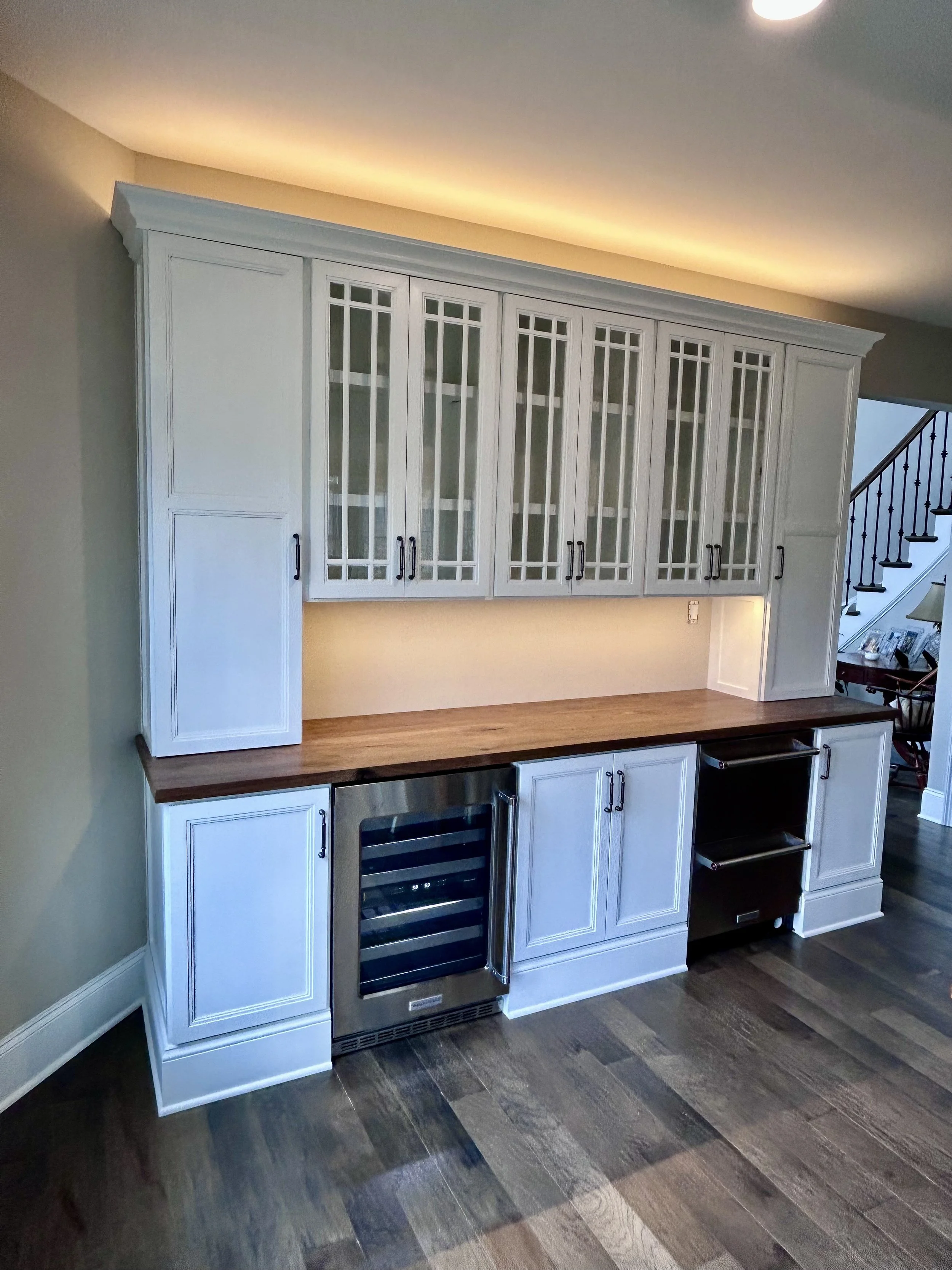  This dining room built-in dry bar with wine fridge and fridge/freezer drawers serves as an extension of the adjacent kitchen for entertaining. The overlay, double-stepped, shaker doors and simulated, divide-lite, glass doors with custom, stepped gri