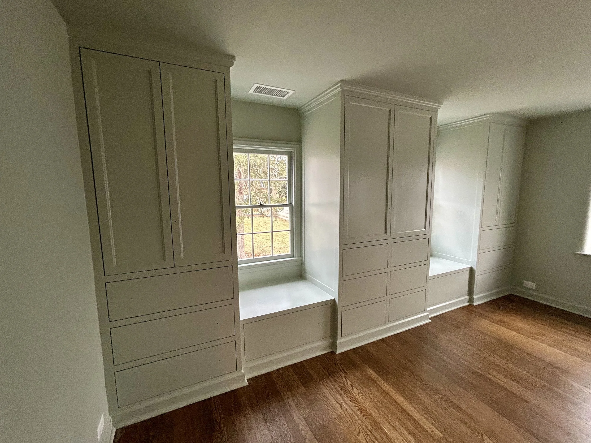  All three closet units have hanging storage of varying lengths. The center unit has mid-length hanging storage,  the right side has slightly shorter hanging space with an extra pull-out shelf behind the doors. The left side closet’s two upper drawer