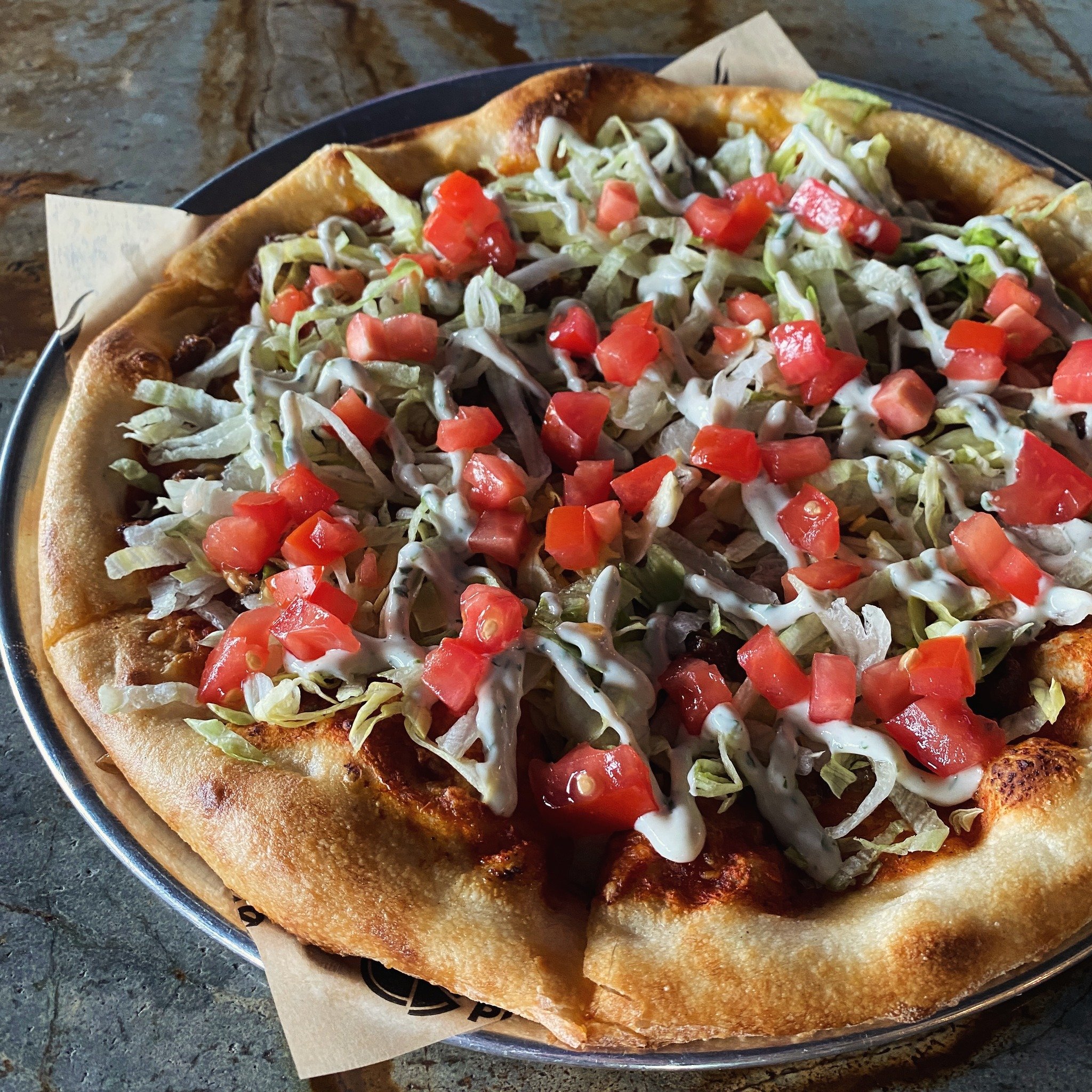 Celebrate Cinco de Mayo and beyond with this month&rsquo;s feature pizza! Taco sauce, seasoned ground beef, red onion &amp; cheddar jack, then lettuce, tomato &amp; cilantro
lime crema after the bake. Make the celebration more festive with our delici