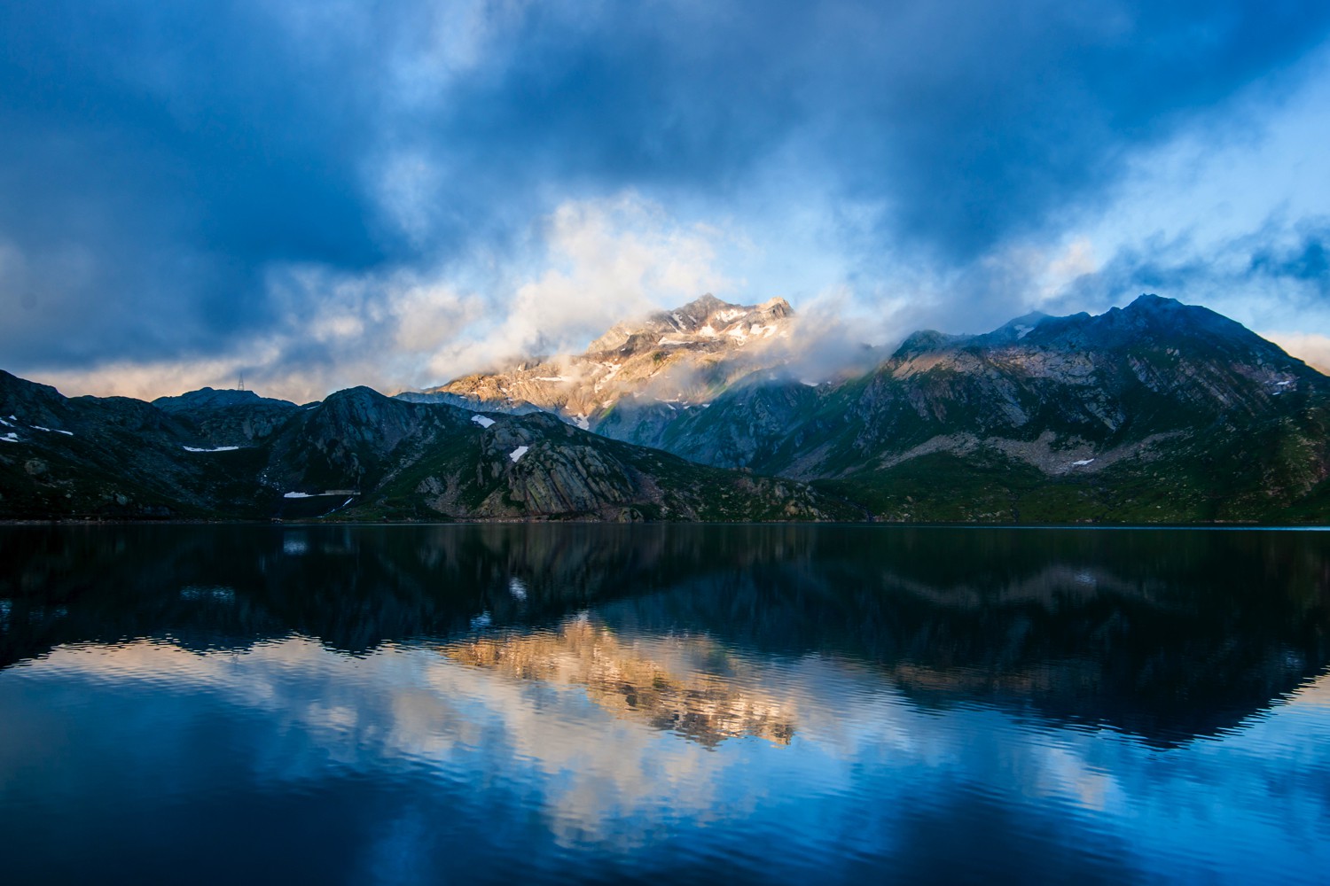 Reflection of mountains on a tranquil lake surface with a cloudy sky.jpeg
