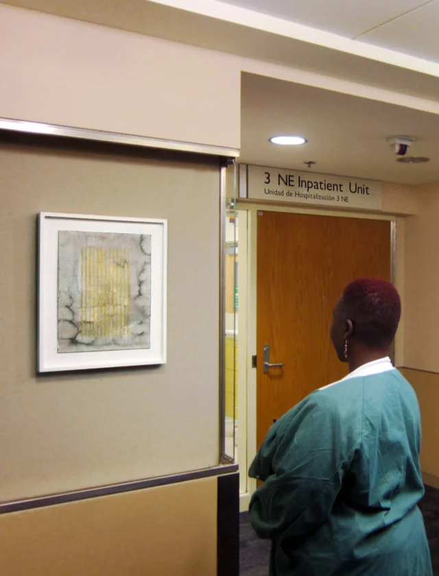 A woman views a painting by Mary Early.