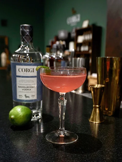 COSMO 2 oz Corgi Spirits Saddlecoat Vodka 3/4 oz Triple Sec 3/4 oz fresh lime juice 1 oz cranberry juice cocktail Add all the ingredients into a shaker with ice and shake. Strain into a chilled cocktail glass. Garnish with a lime wedge.