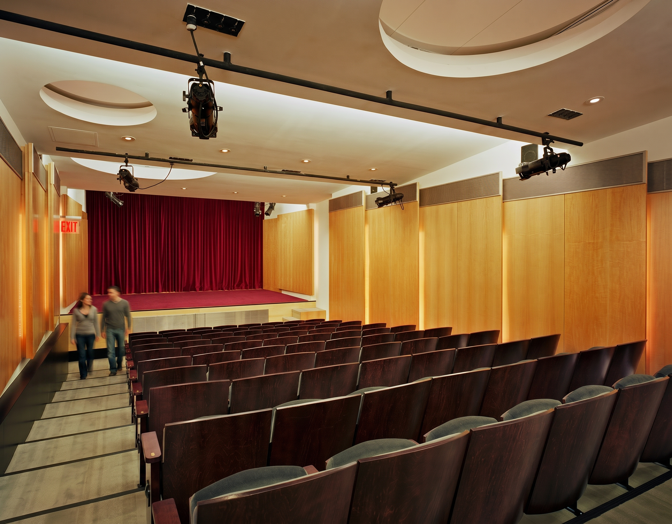 Lower-ground-floor auditorium with illuminated skylights connecting to atrium above within multi-modal performance space in Manhattan