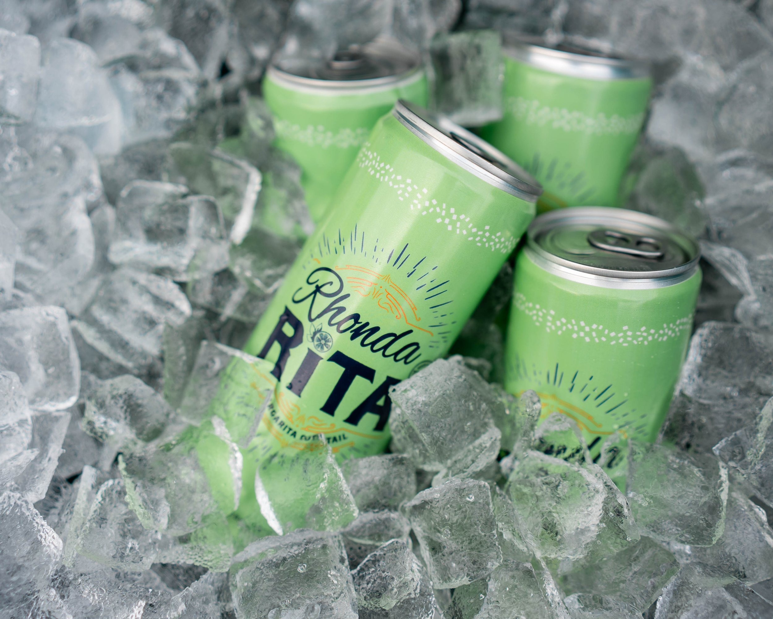 Several green canned beverages labeled 'Rhonda Rita' nestled in ice cubes.