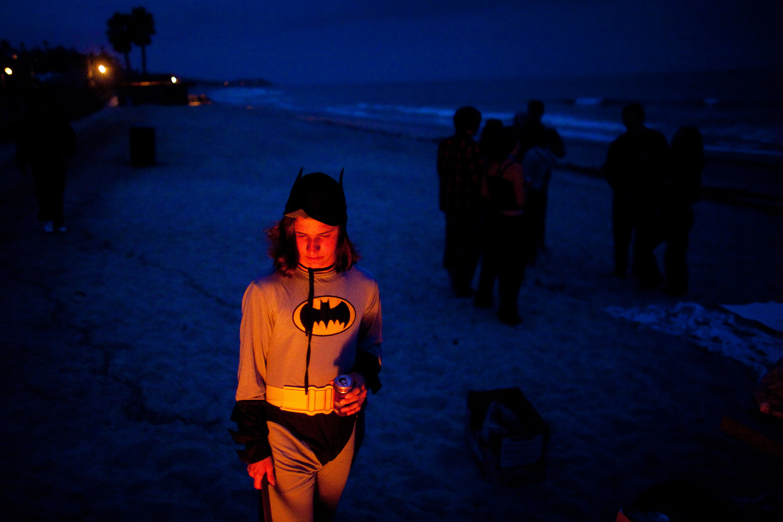 Brendon Cooney, a student at the Orange County High School of the Arts, stands near a bonfire dressed as Batman on the beach by the pier. A group of students had the bonfire to celebrate the end of the school year by burning their schoolwork.