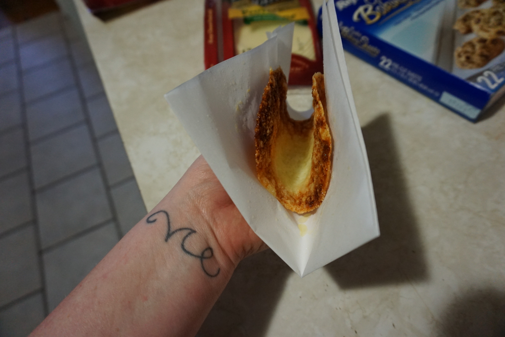 Grab the parchment paper while the cheese is still hot and fold it like this and hold it for about 30 seconds or until it is cooled enough to keep a taco shell shape.