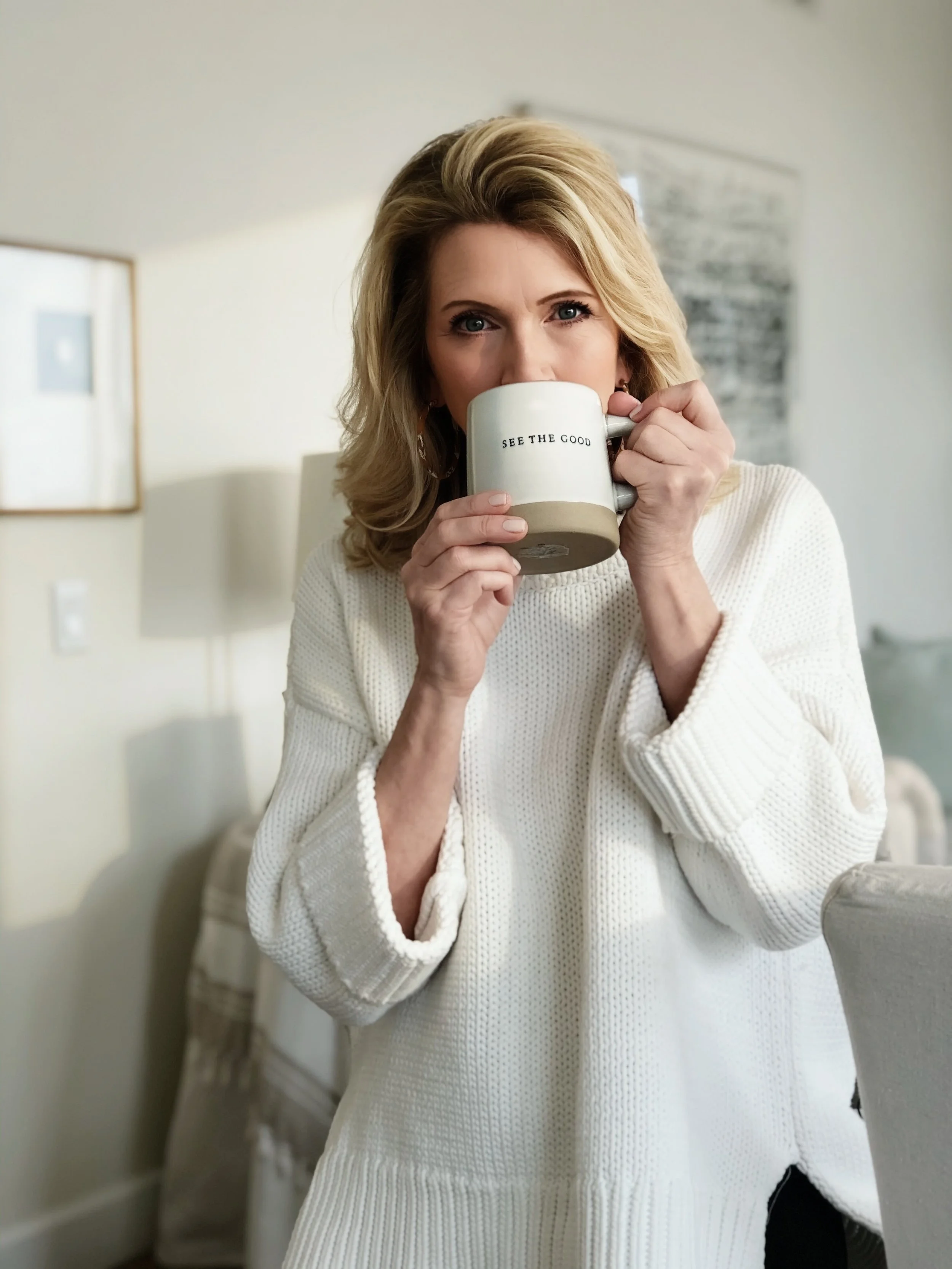 kimberly in a white sweater hold a coffee mug that says, "Life is Good"