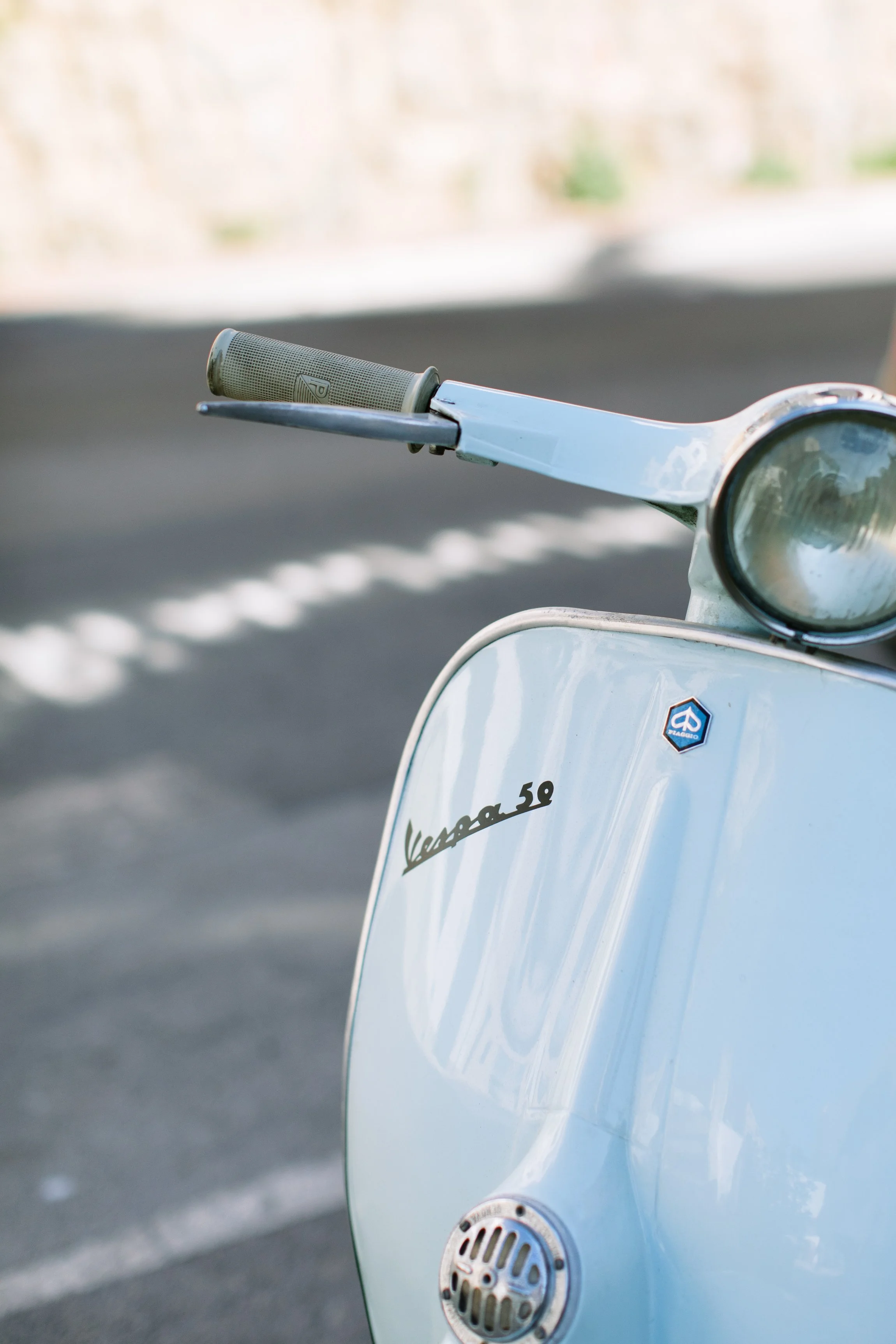 the front bumper and handlebars of a light blue vespa