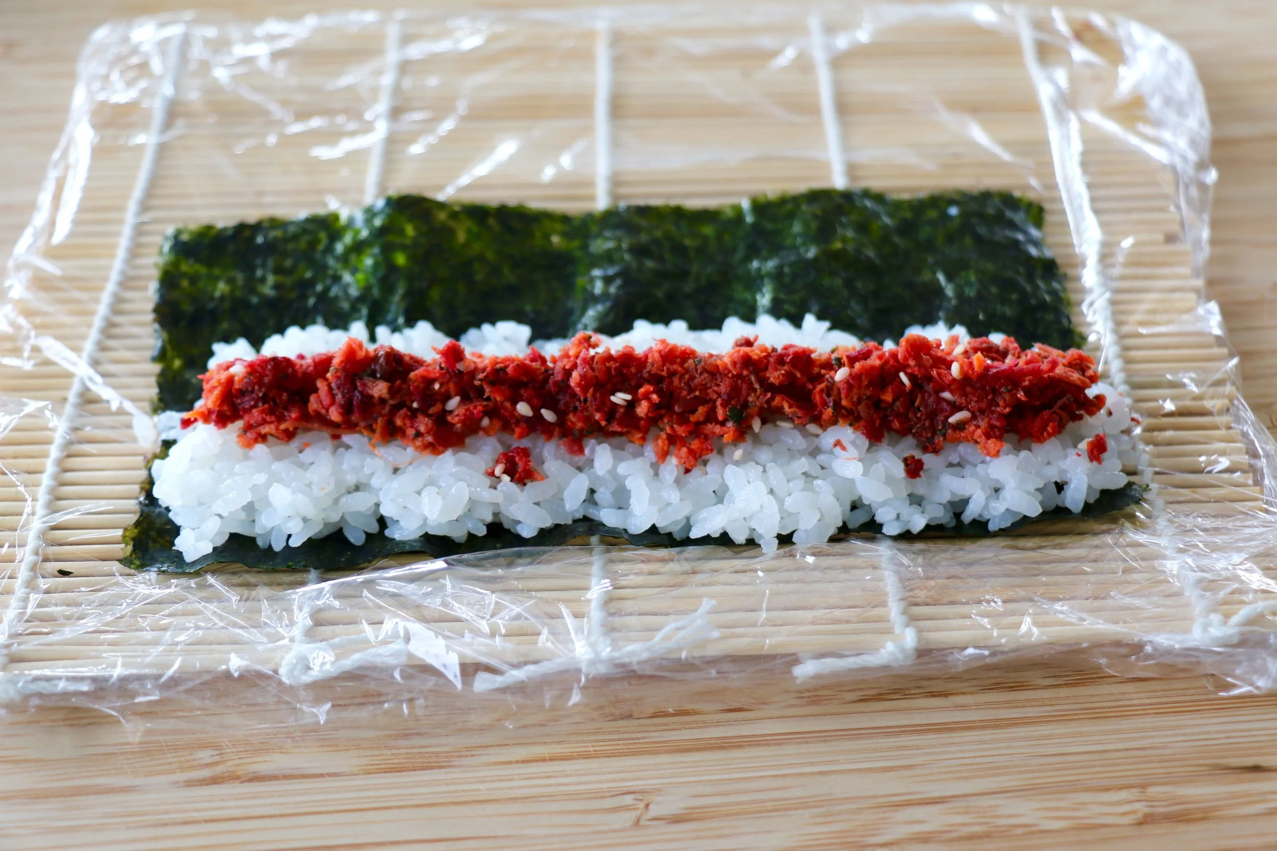 Thin layer of rice on a quarter of the nori sheet with some pickled Juicero beet pulp