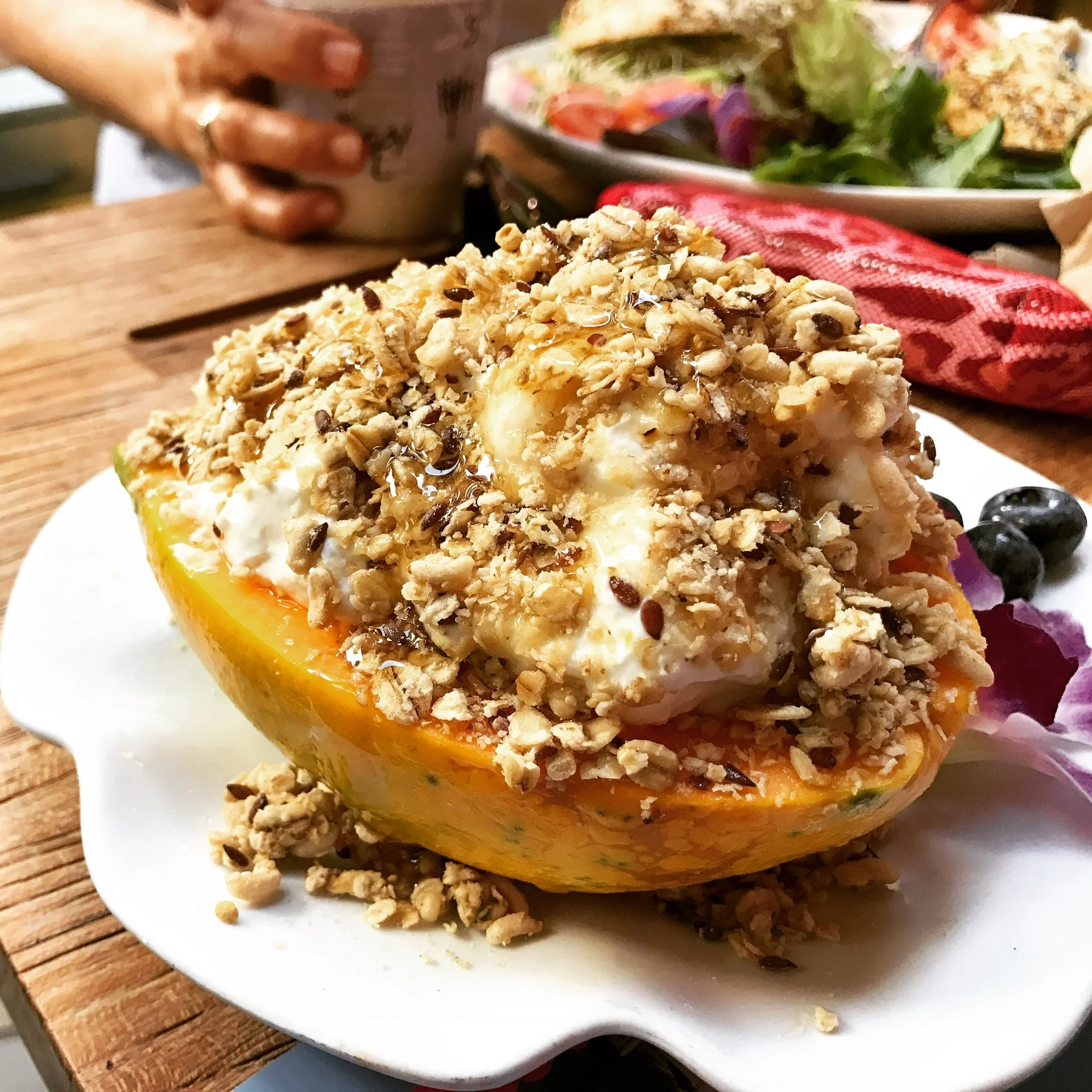 Yogurt Parfait served in inside a local Hawaiian Papaya. House made granola with local honey and also a side of sliced bananas and strawberries to pair with it hidden behind the papaya