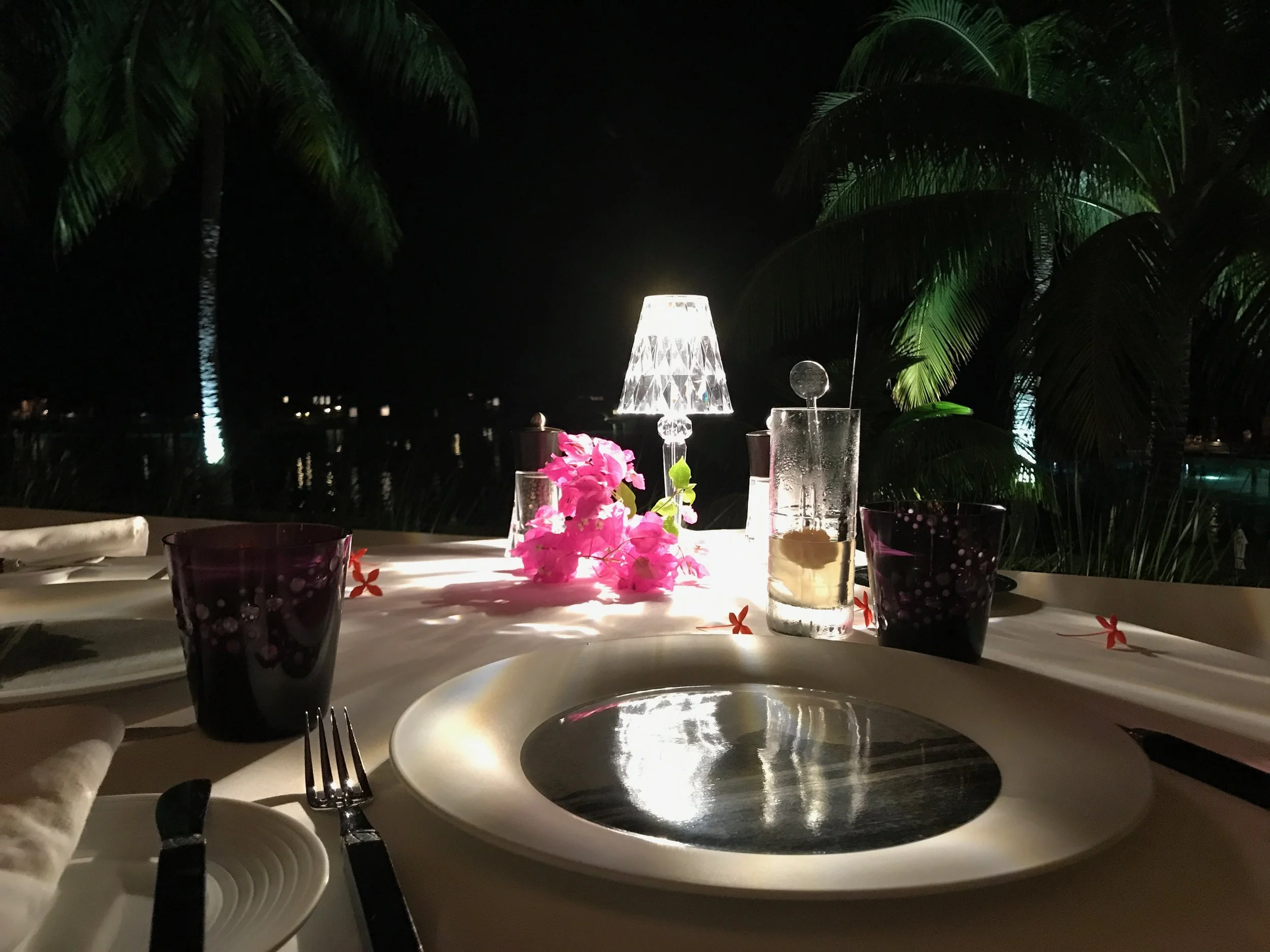 Request a romantic table on the terrace with a view of the water at night at the Iriatai