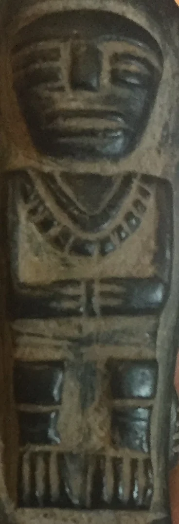 The triangle above this figures necklace identifies it as a female adult.