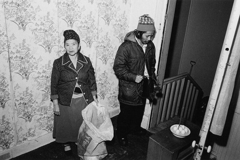 Joua Yang inviting spirits to enter the home.  The bag contains live chickens which are to be sacrificed in a New Year ceremony.  Oshkosh, WI  1985