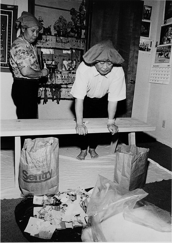 Shamans Nyia Houa Xiong & Nyia Vang inspecting spirit paper. Oshkosh, WI 1988