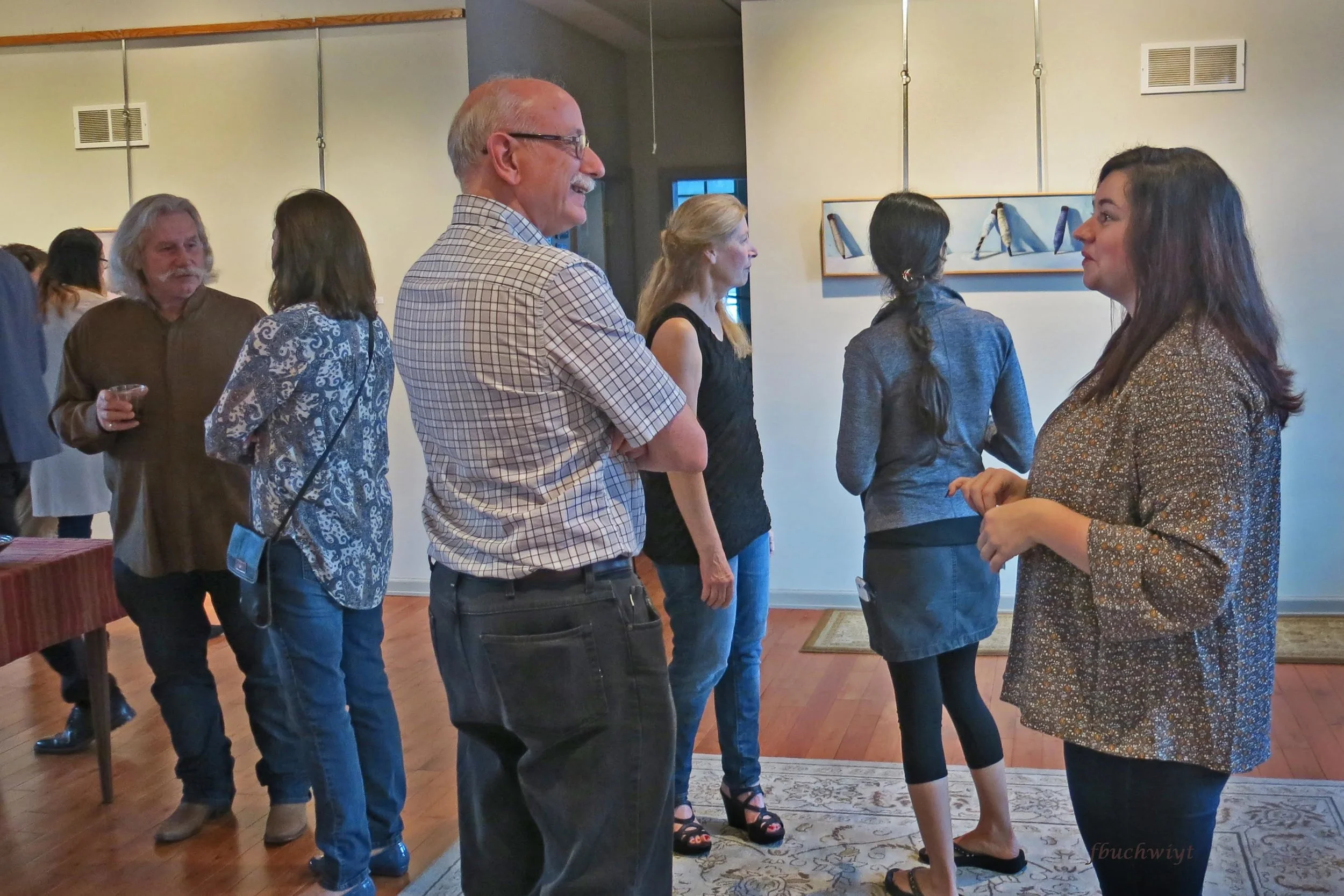 Claira talking to LHU Art professor, Raymond Heffner, while people enjoy the exhibit.