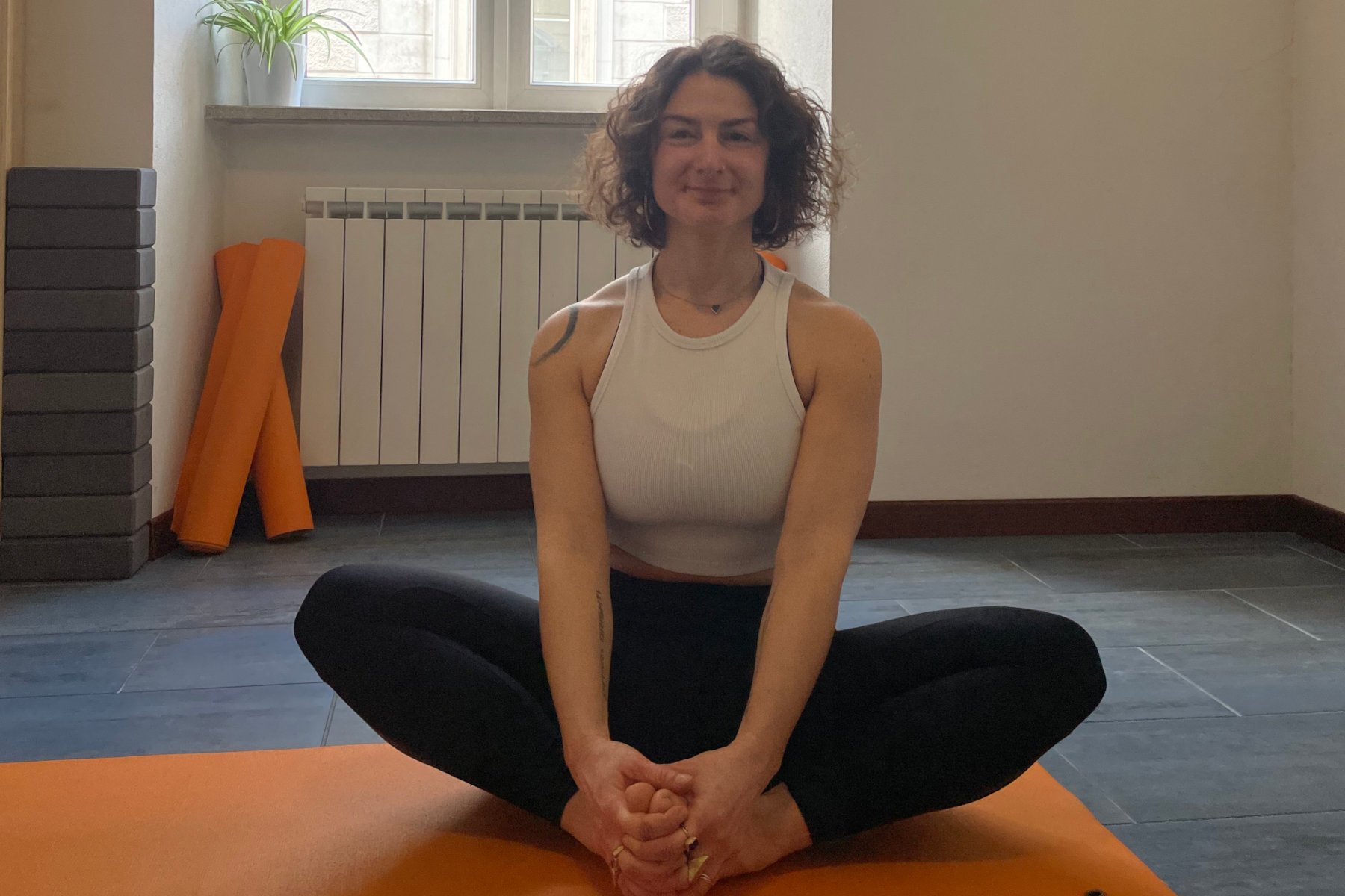 Micol seduta in una posizione di yoga su un tappetino nello studio Yoga Trieste.