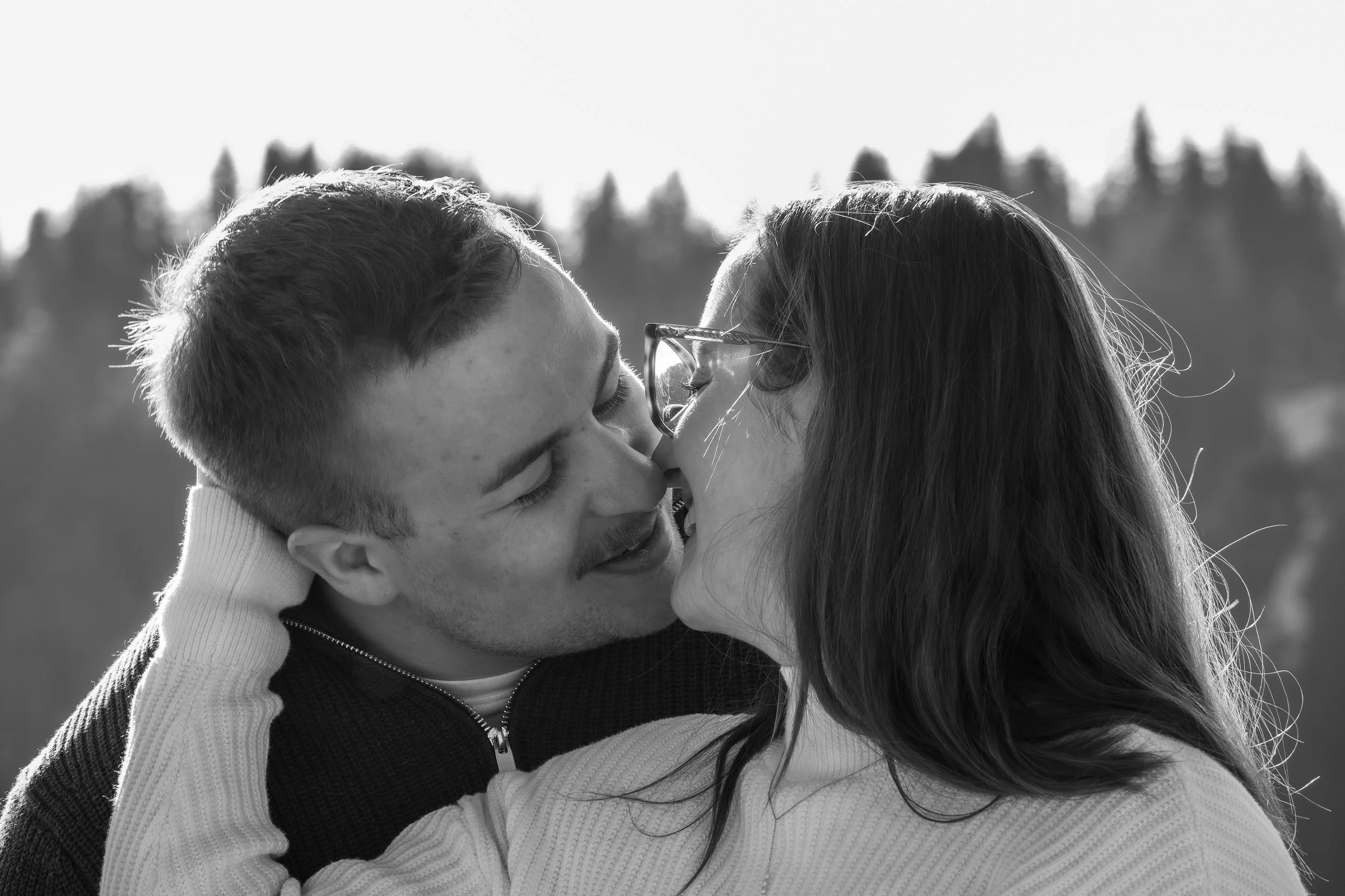 Un couple s'embrassant en plein air, en noir et blanc.