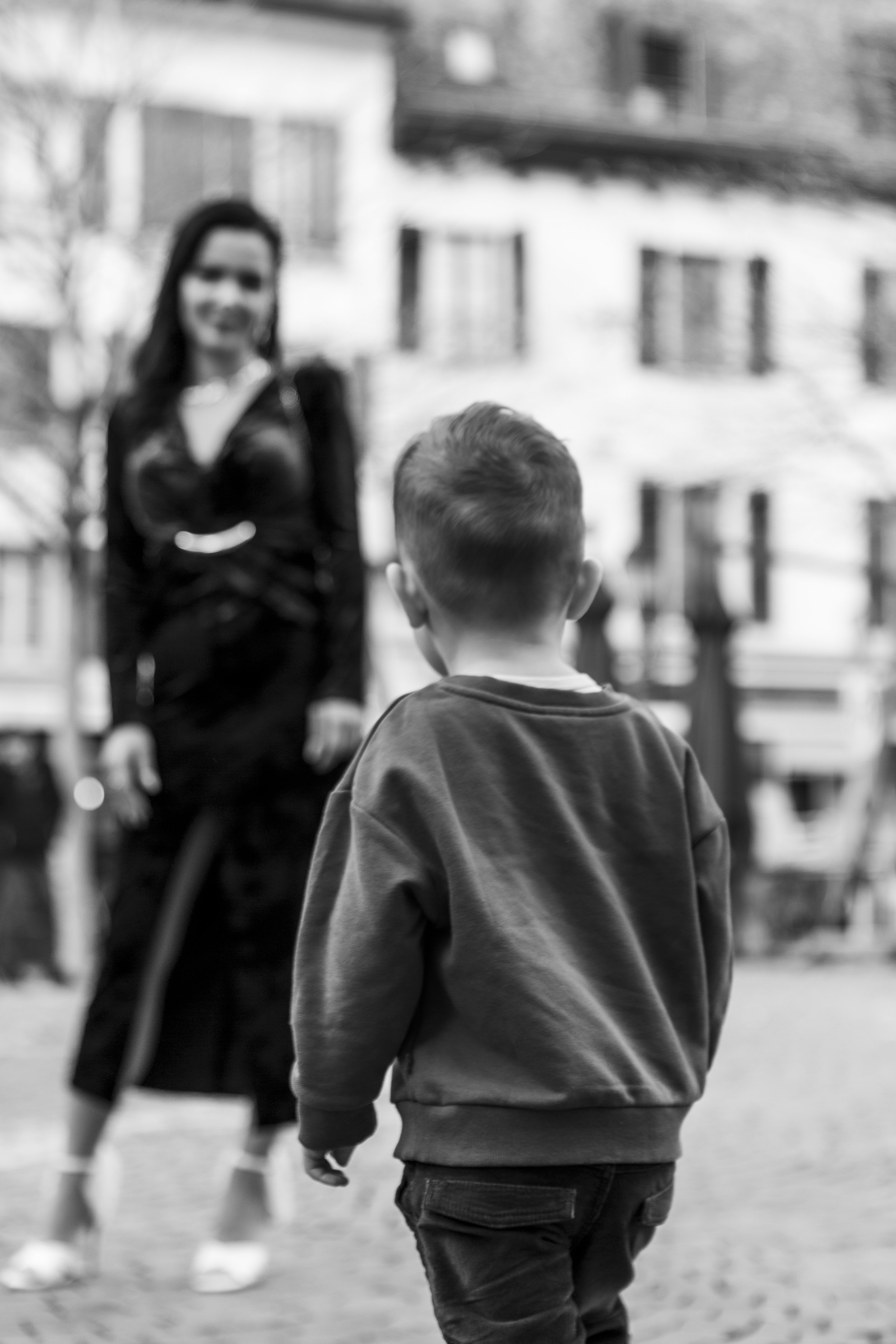 Un garçon vu de dos, regardant une femme en face, dans un environnement extérieur.
