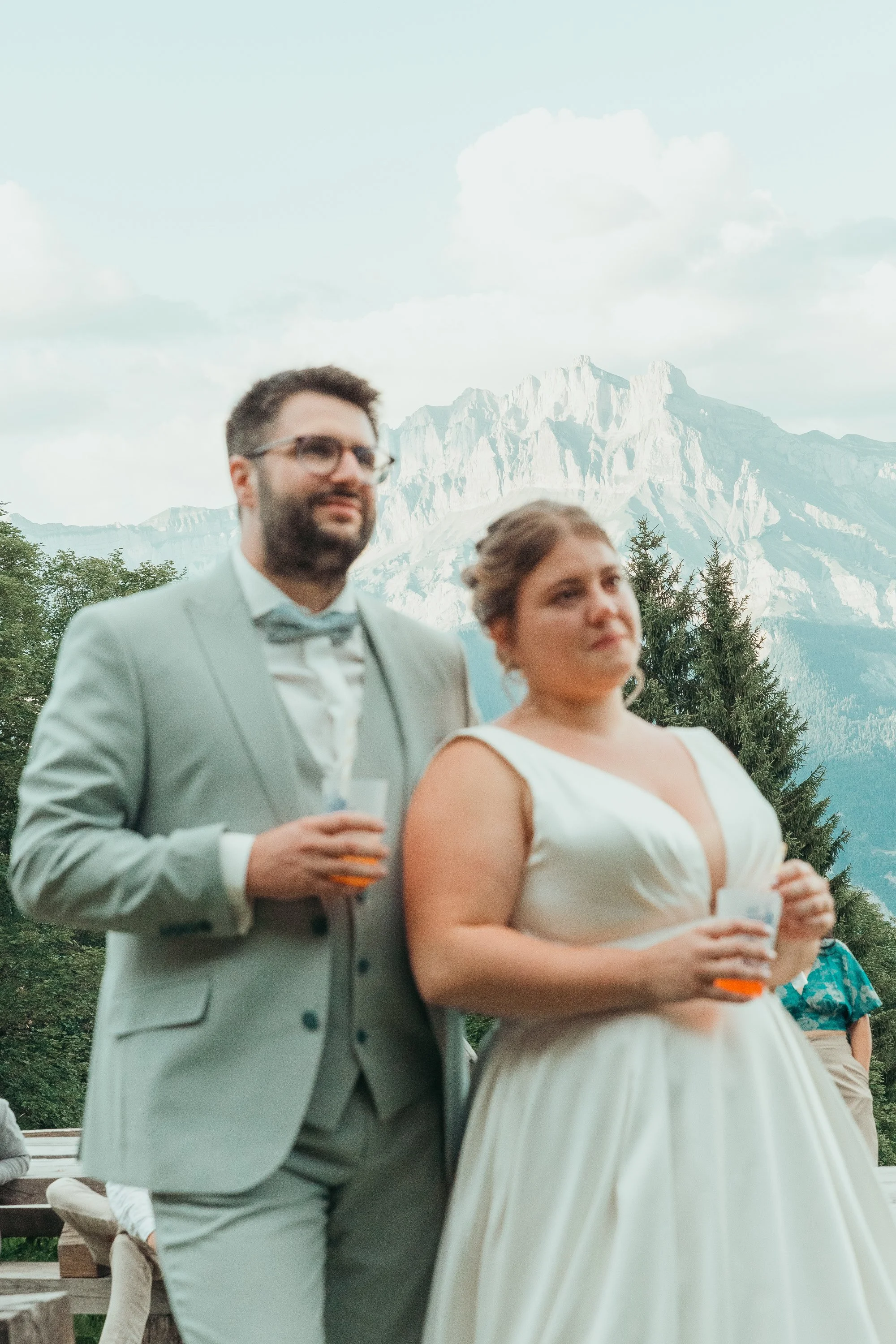 Un couple en costume de mariage avec un paysage de montagnes en arrière-plan, le Mont-blanc lors d'un reportage mariage avec Marie Monod photographe d'émotions, duo de photographes queer en Suisse.