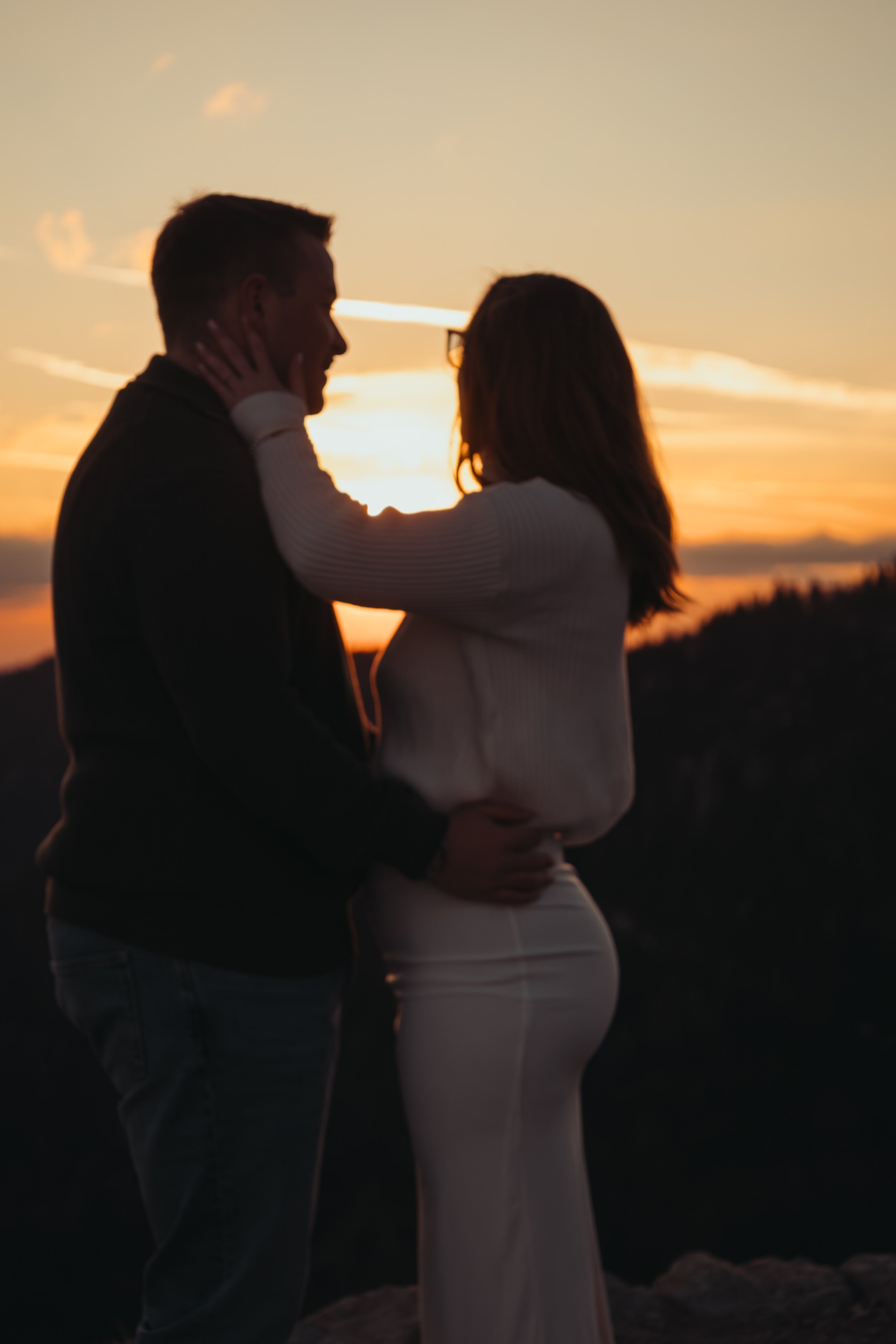 Un couple qui se tient face à face lors d'un coucher de soleil, où l'homme tient le visage de la femme dans ses mains.