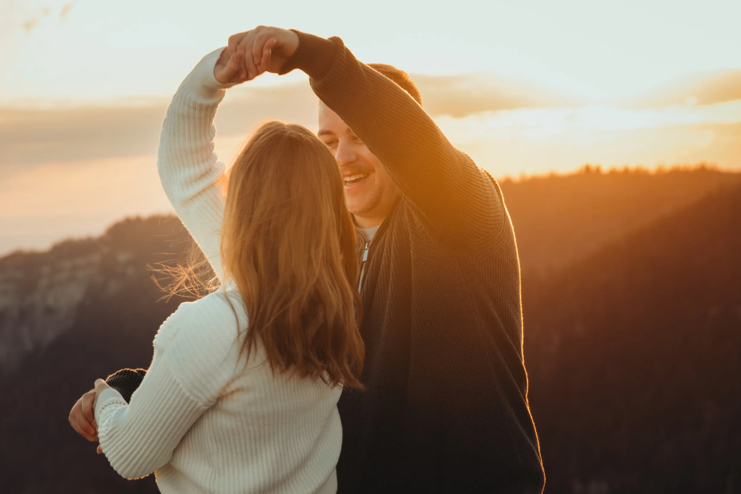 Un couple danse sous le coucher de soleil dans un paysage naturel.