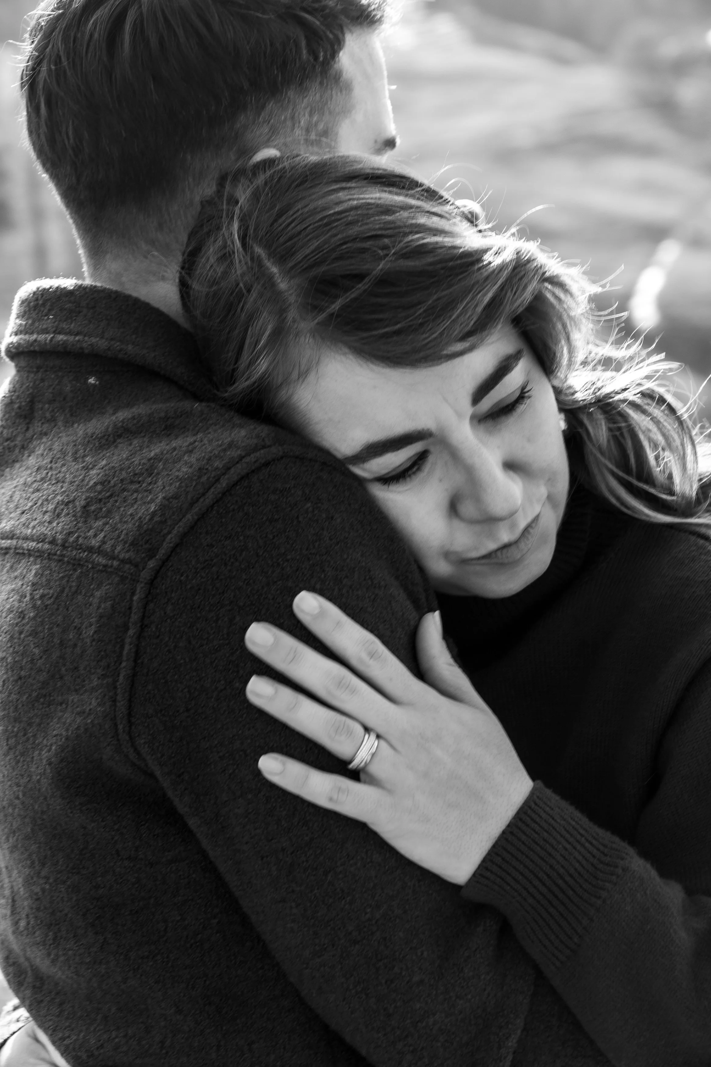 Un couple en étreinte, les yeux fermés, avec un sourire chaleureux. La femme repose sa tête sur l'épaule de l'homme, tous deux dégagent du bonheur et de l'affection.