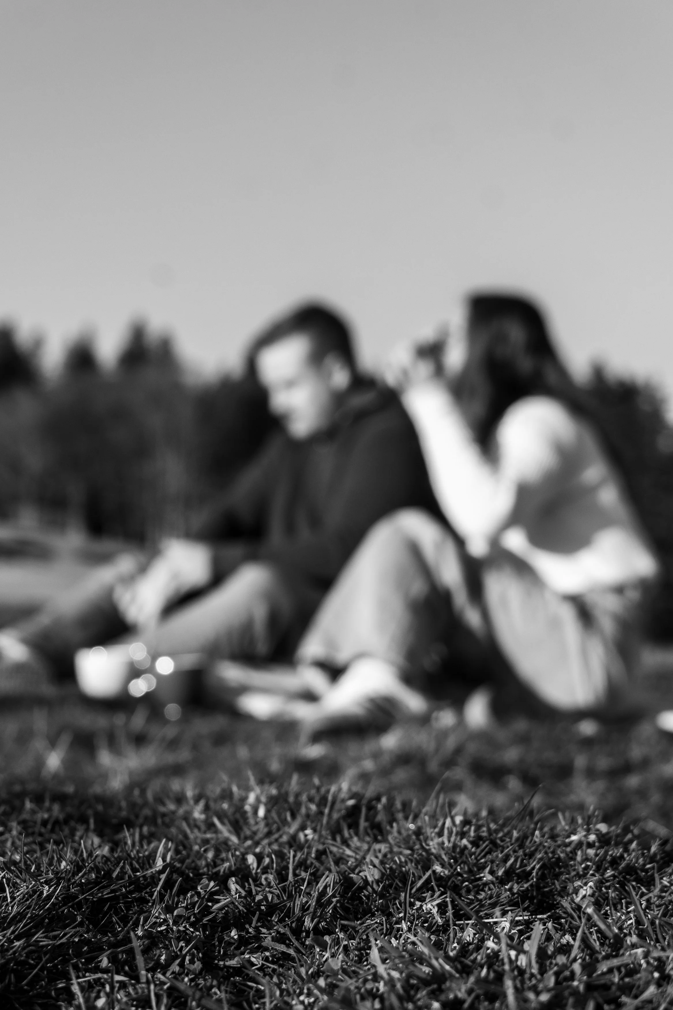 Deux personnes assises sur l'herbe, vue floue, notamment un homme et une femme.