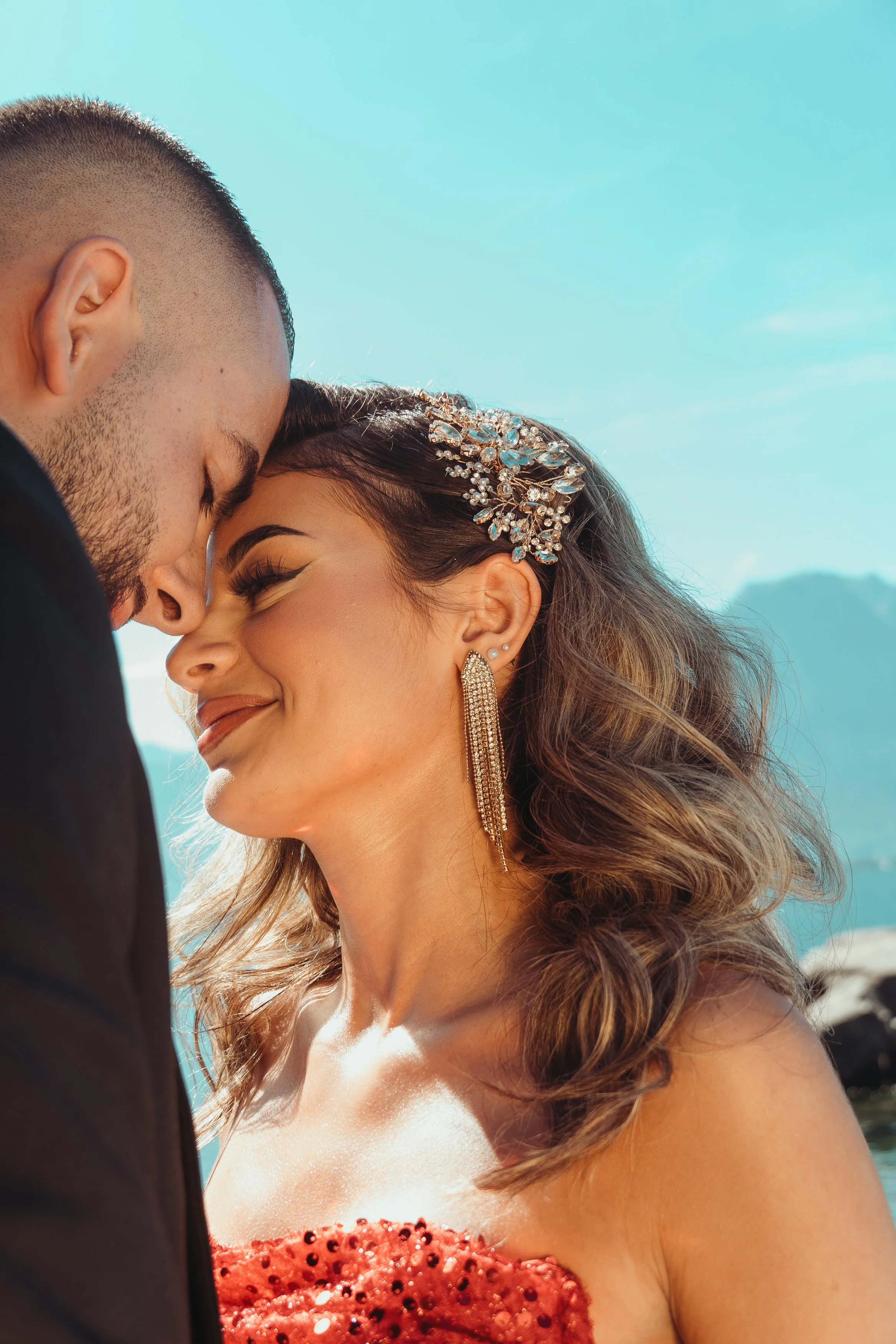 Un couple souriant proche avec le front touchant, lors d'une séance photo en plein air, ensoleillée lors d'une séance couple avec Marie Monod photographe d'émotions, duo de photographes queer en Suisse au lac léman