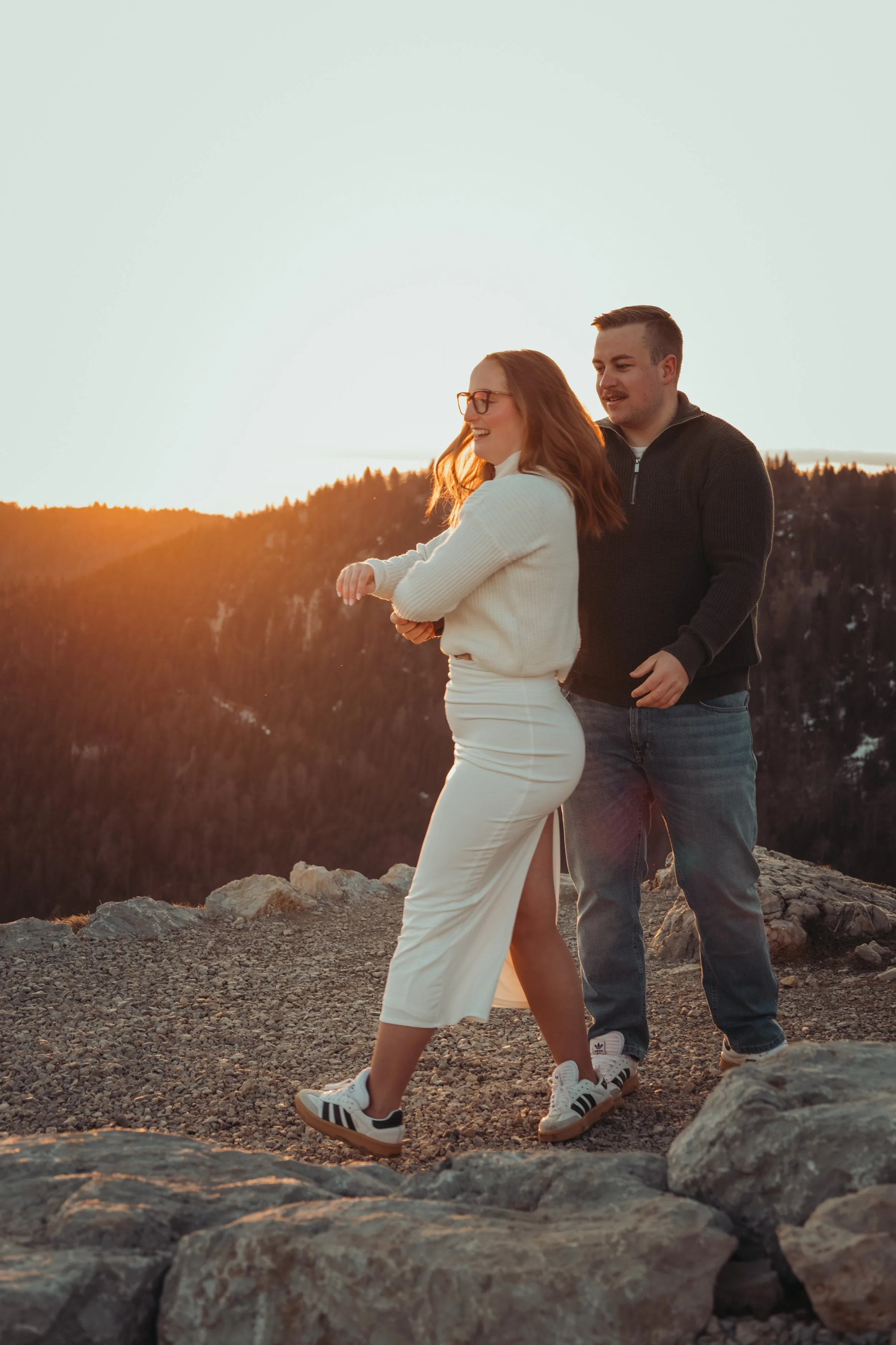 Un couple marche et partage un moment de bonheur au coucher du soleil dans un paysage montagneux.