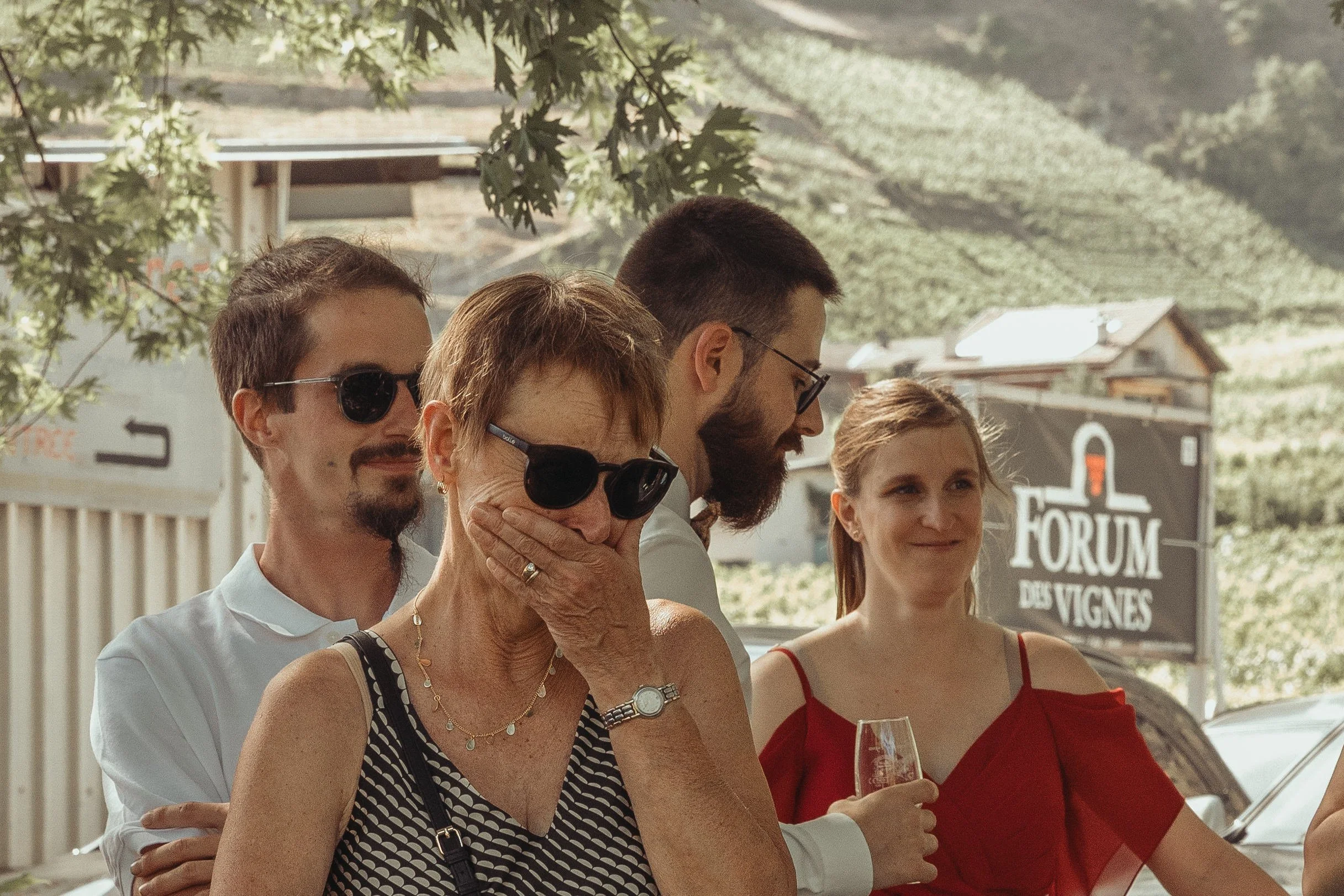 Groupe de cinq personnes assises en extérieur lors d'un événement, avec des montagnes en arrière-plan et un panneau indiquant "Forum des Vignes".
