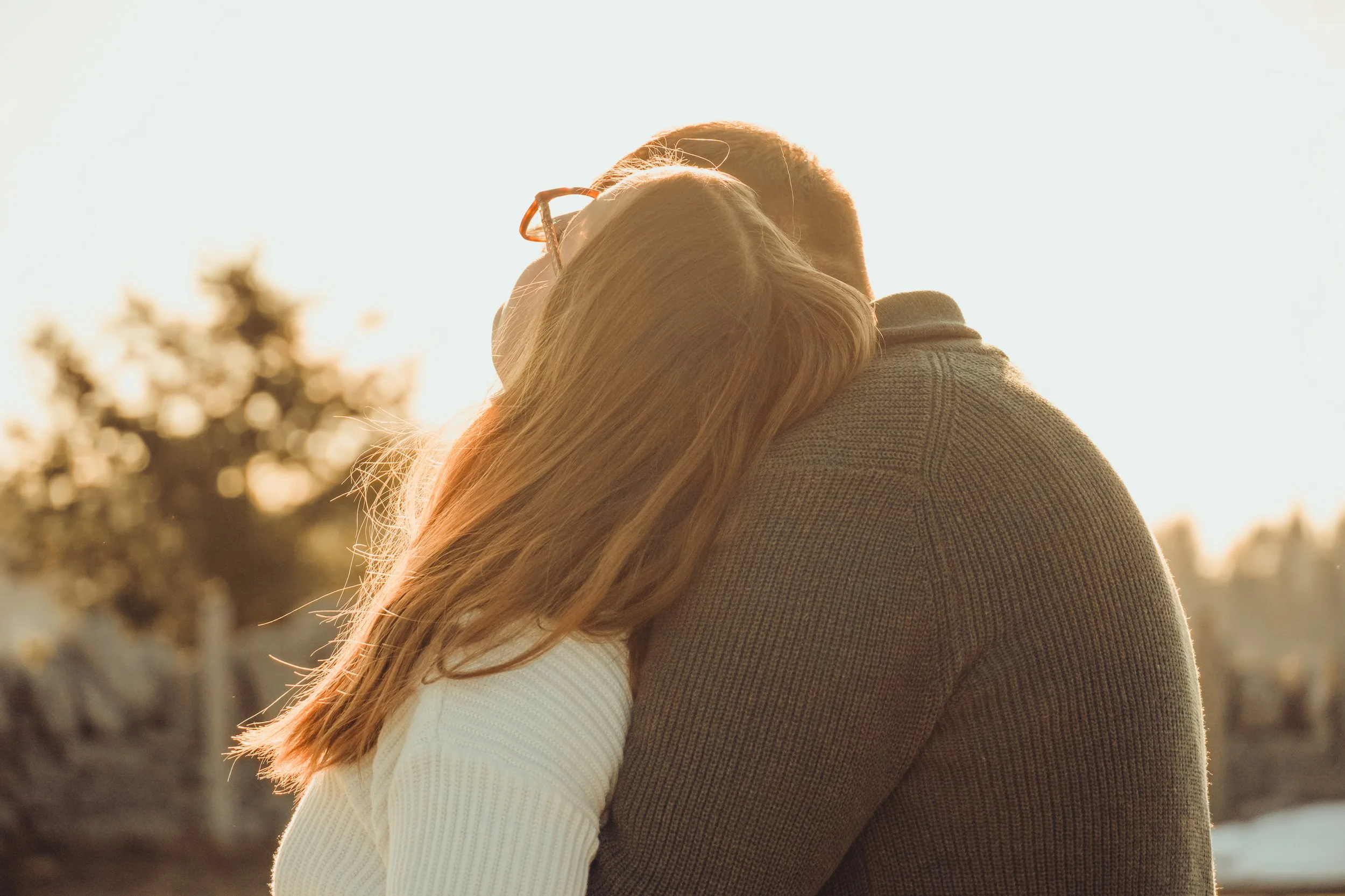 Un couple se serre dans une étreinte chaleureuse en plein air lors du coucher du soleil.