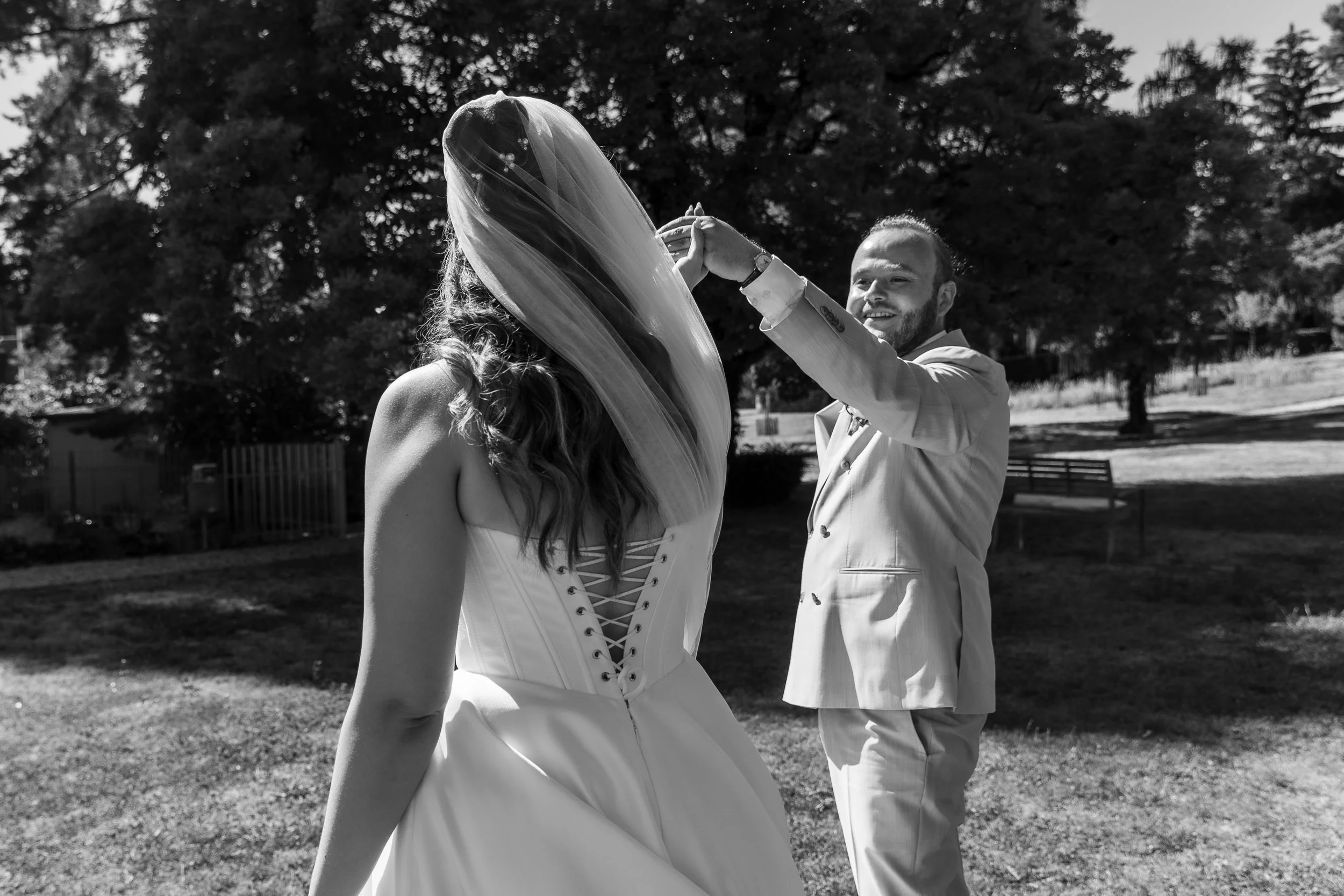 Un couple de mariés danse en plein air lors d'une cérémonie nuptiale en chien de noir et blanc, avec des arbres en arrière-plan.