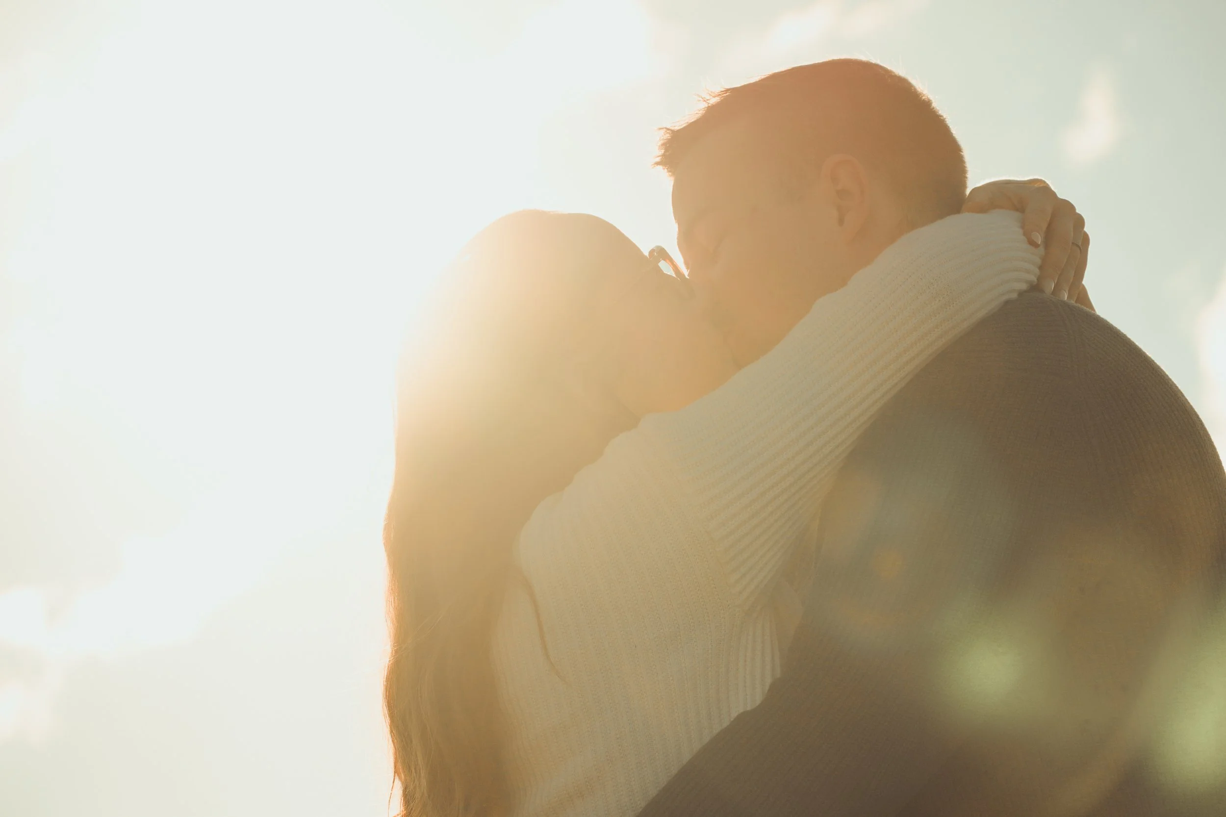 Un couple qui s'embrasse à l'extérieur au coucher du soleil.