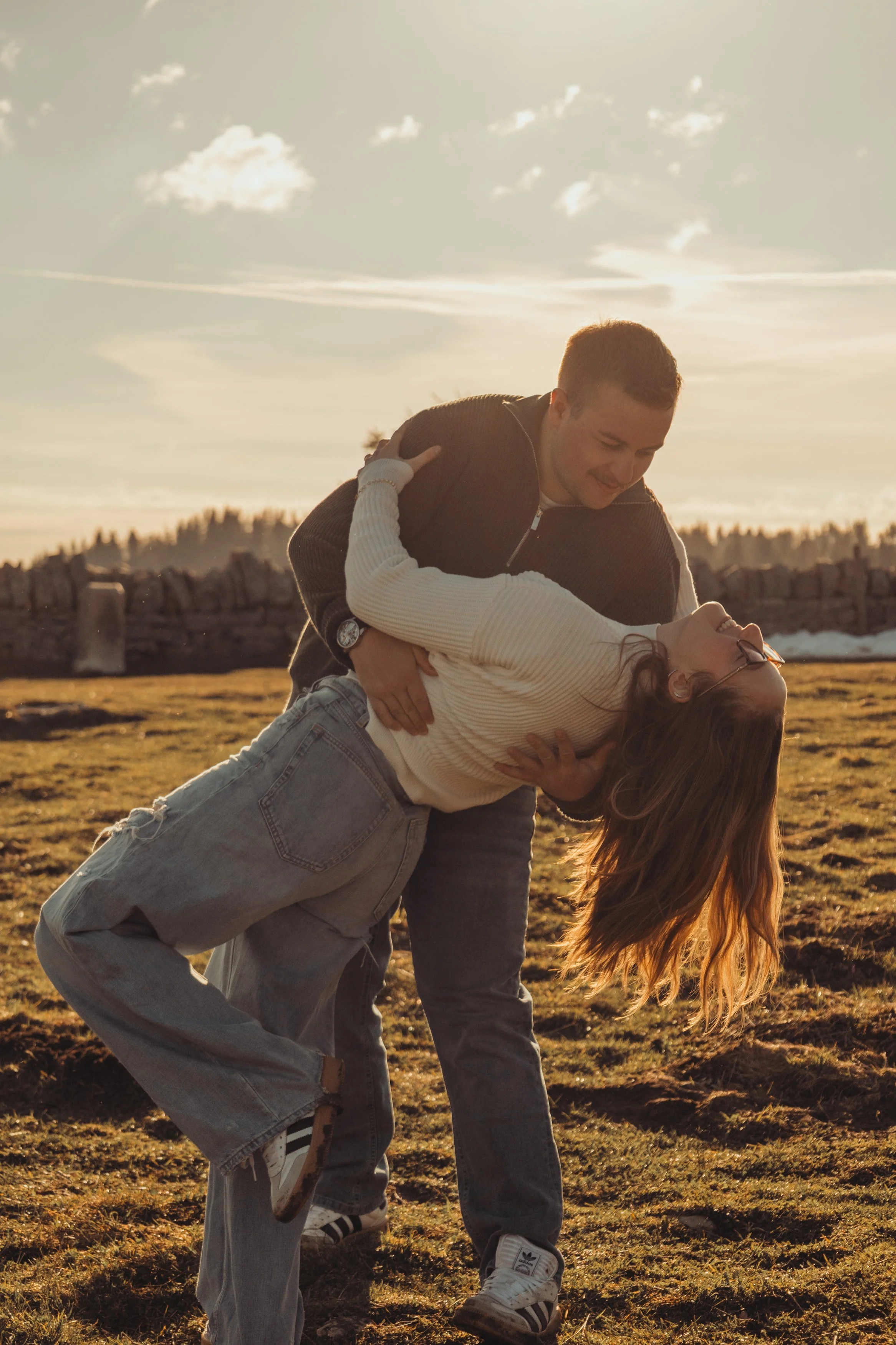 Un couple danse dans un paysage extérieur au coucher du soleil, avec un garçon tenant une fille en position de danse.