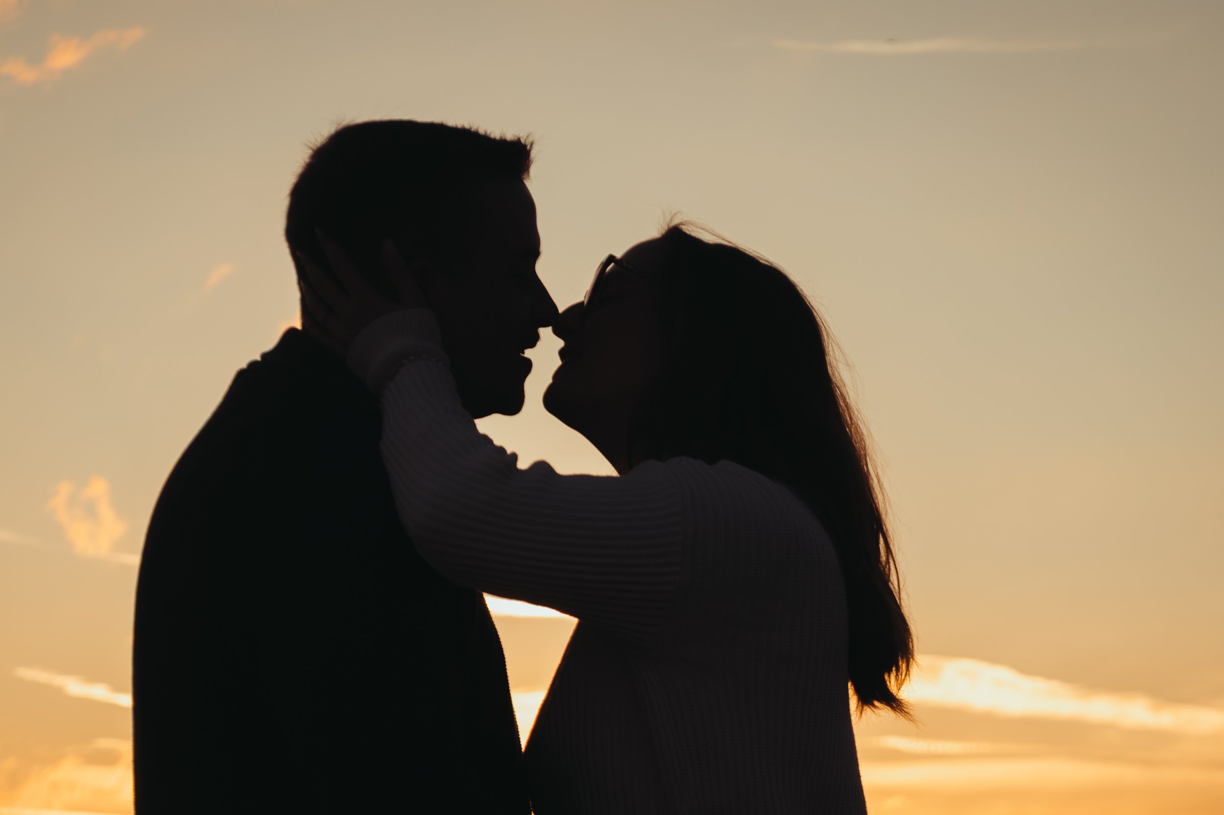 Silhouette d'un couple qui s'embrasse lors d'un coucher de soleil.