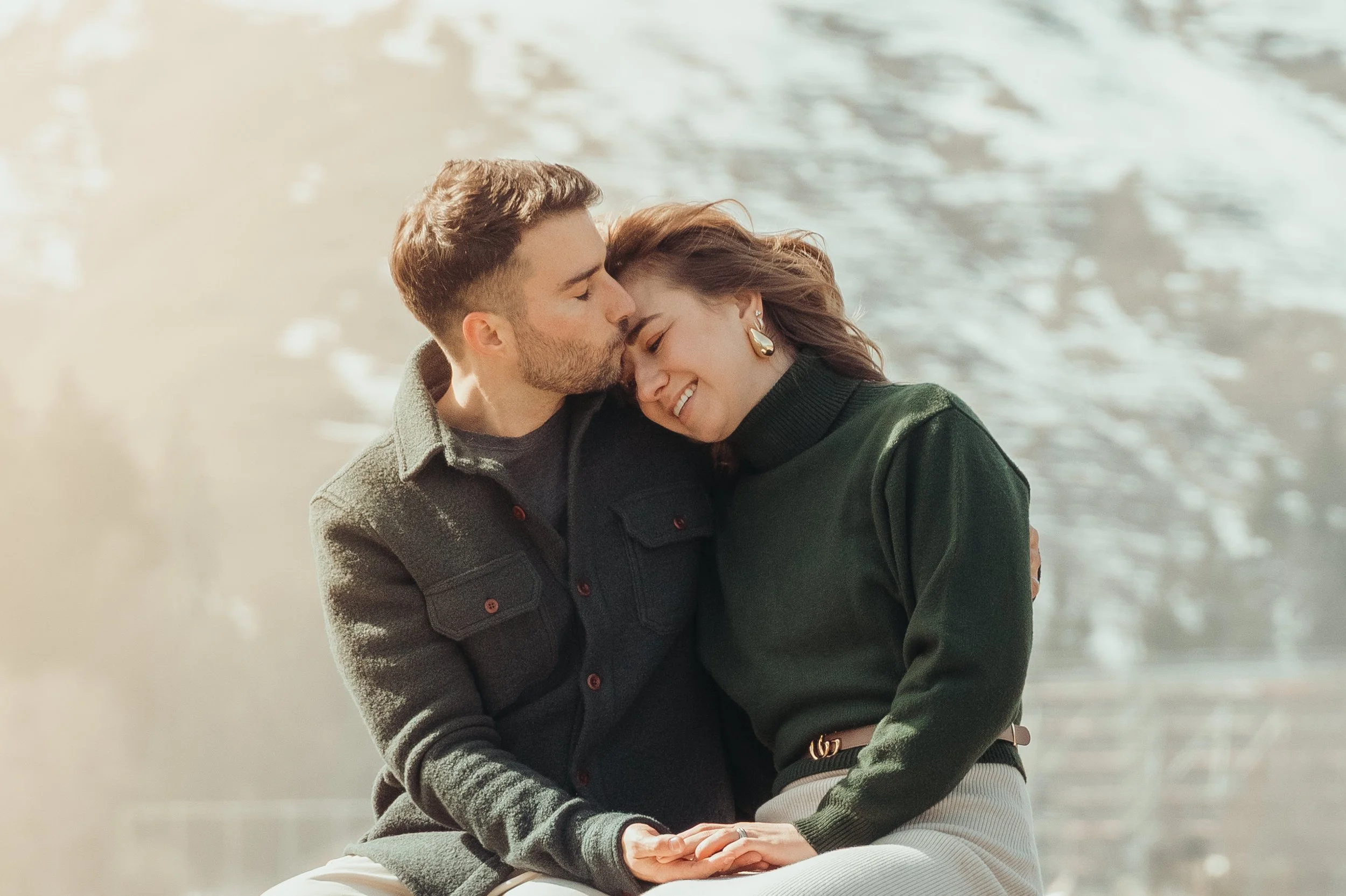 Un couple souriant et enembrassé près d'un plan d'eau, partageant un moment intime.