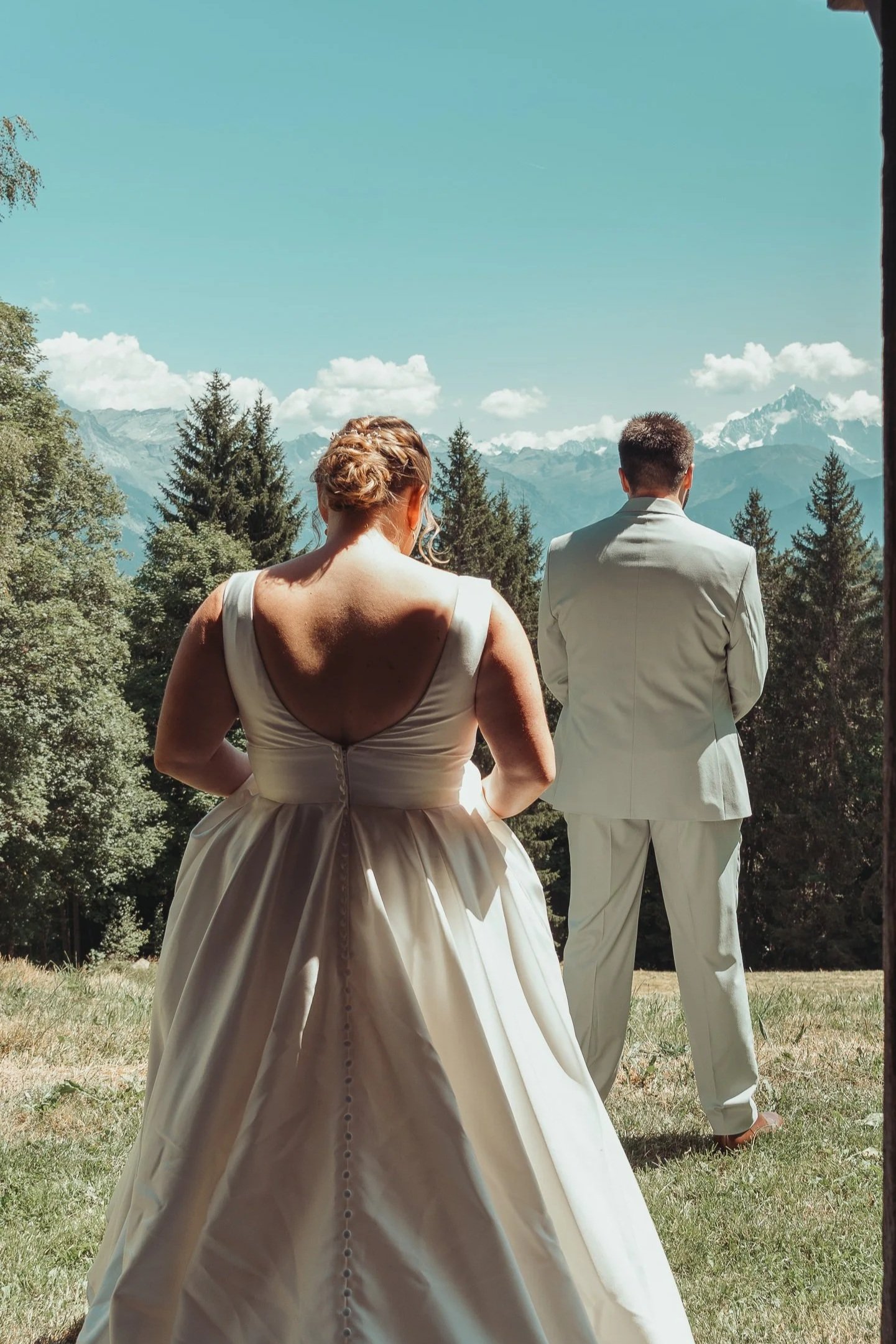 First look entre la mariée et le marié à l'extérieur, avec un paysage montagneux et des arbres en arrière-plan lors d'un reportage mariage avec Marie Monod photographe d'émotions, duo de photographes queer