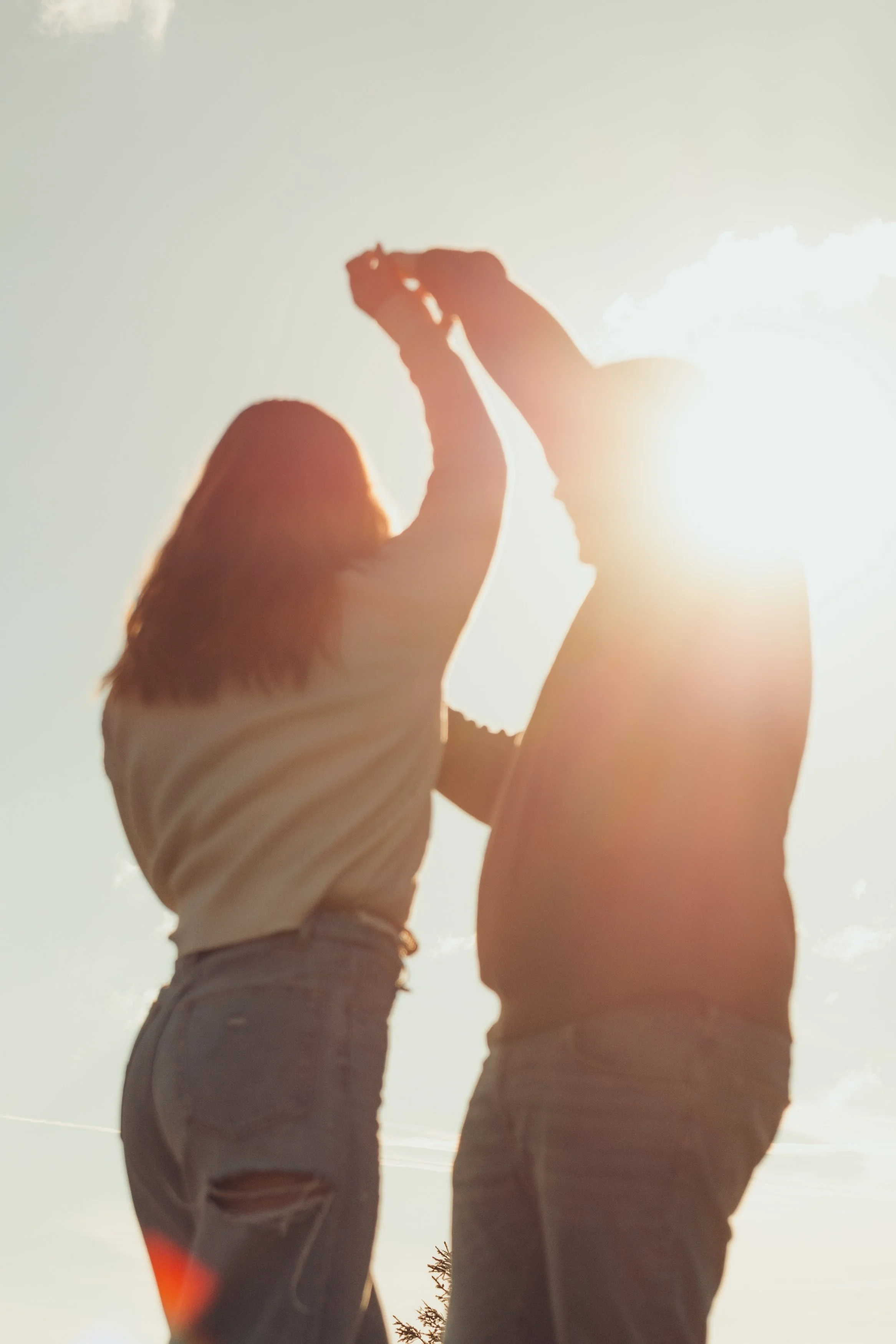 Deux personnes, une adulte et un enfant, se tiennent par la main au coucher du soleil.