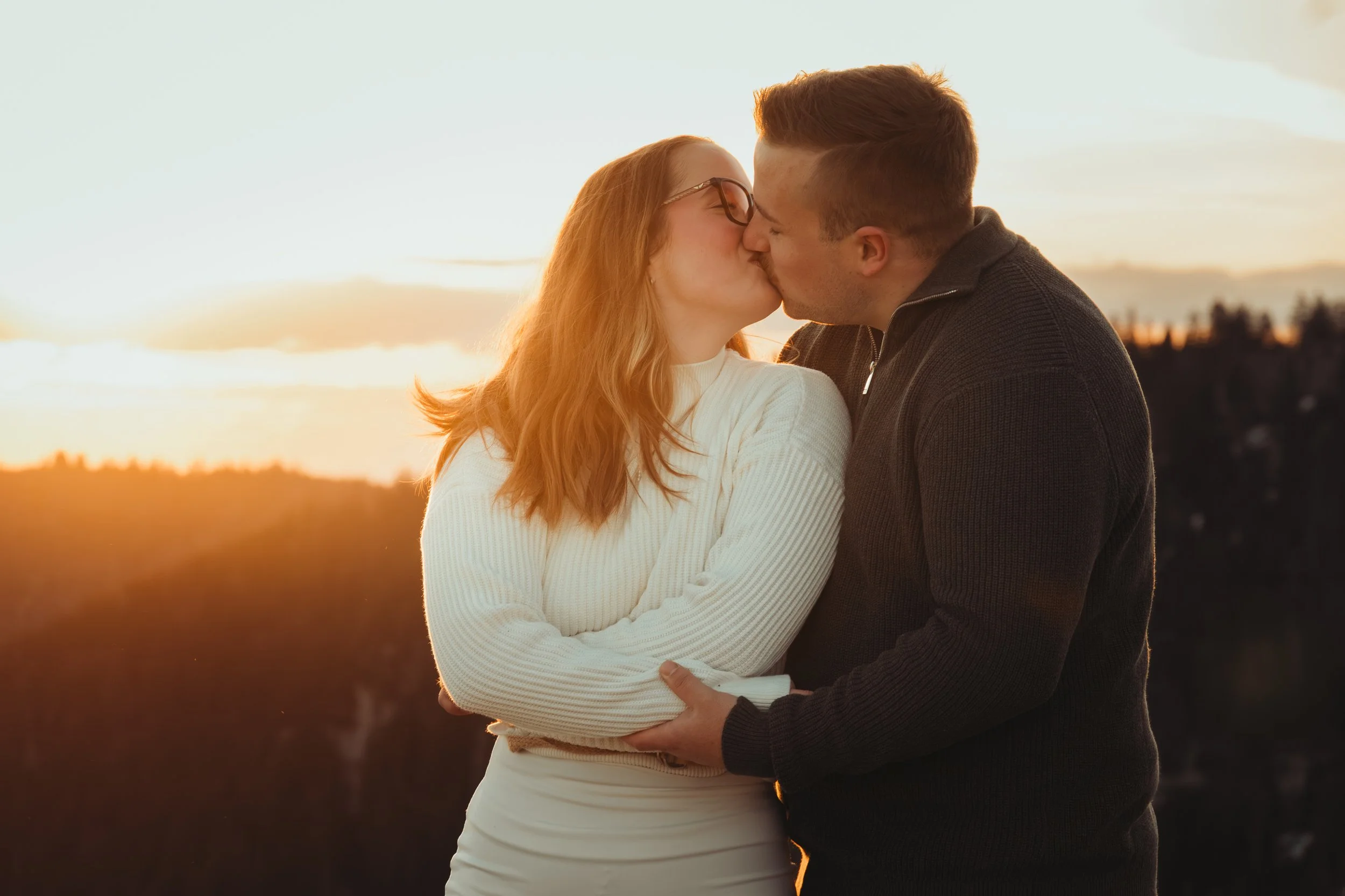 Un couple s'embrasse lors d'un coucher de soleil dans un paysage naturel.