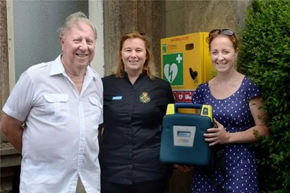 From left, Peter Coleman, Linda Richter and Katie Thomas by the defibrillator in its new position outside the box office door